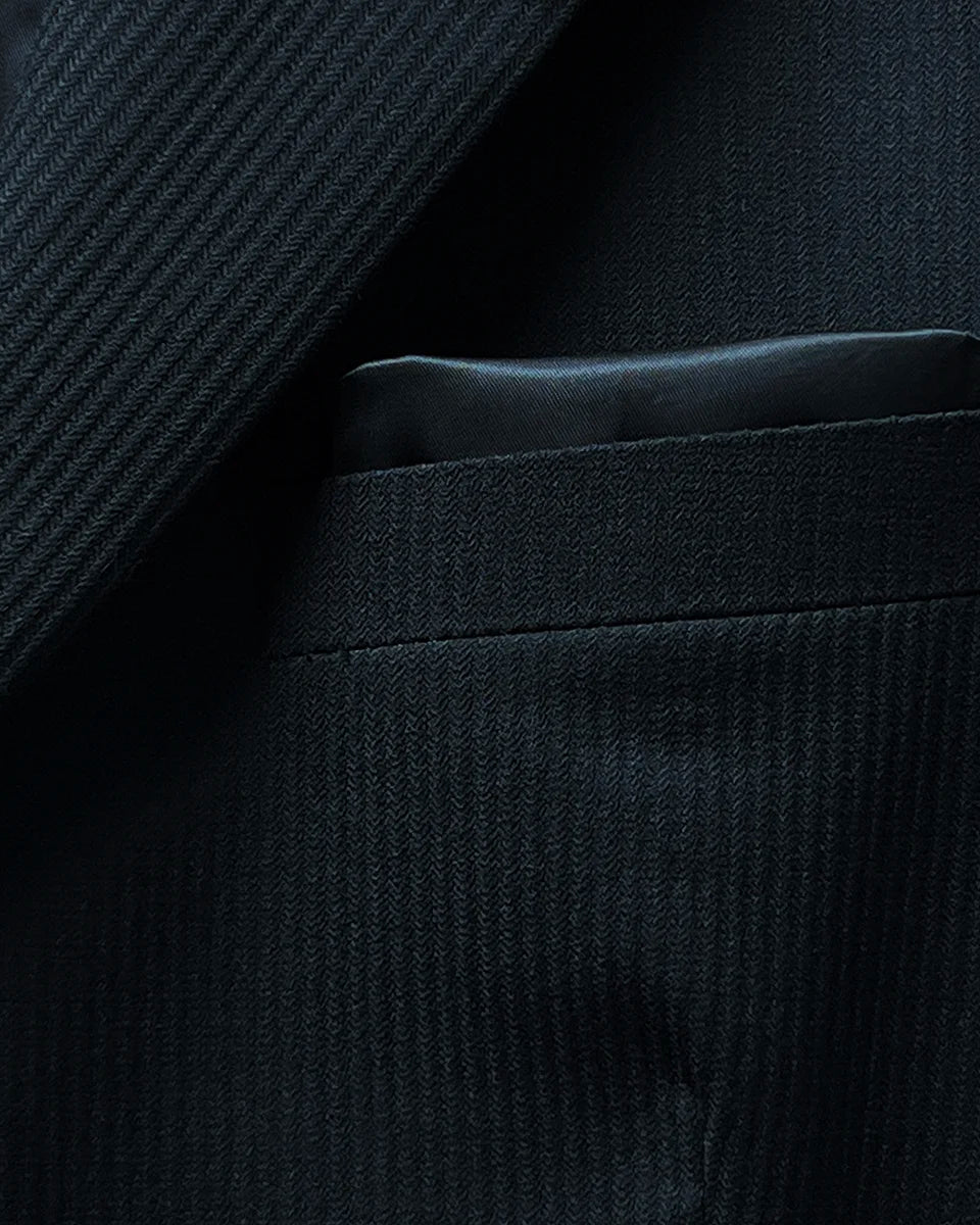 View of the built-in pocket square in the jacket's pocket, complementing the black herringbone fabric.