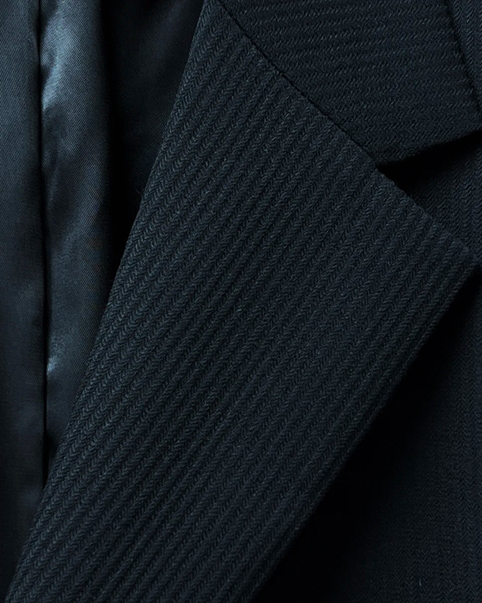 Close-up of the notch lapel, showcasing the black herringbone design and tailored finish.