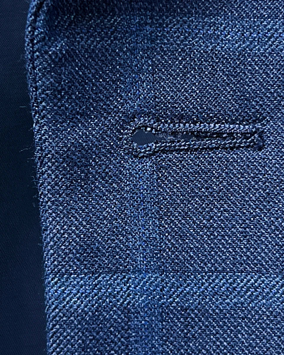 Macro view of the precise hand-stitching around buttonholes on the Indigo Blue Windowpane sport coat