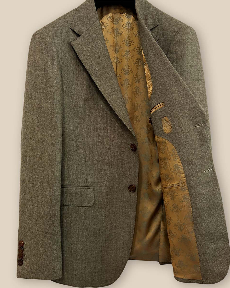 Inside view of the left side of the Westwood Hart brown nailhead men's suit jacket, revealing the gold patterned lining and interior pockets.