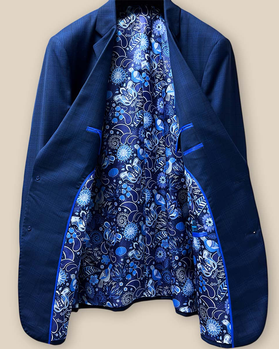 Full view of the interior lining of the dark blue windowpane men's sport coat with blue and white aviary motif flash lining and royal blue piping.