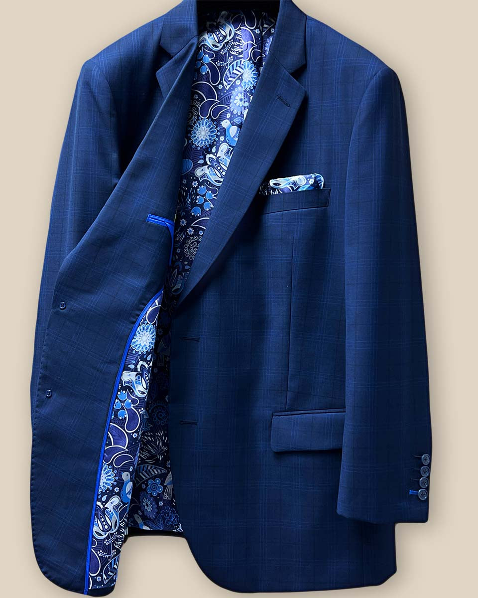Interior view of the right side of the dark blue windowpane men's sport coat highlighting the blue and white aviary motif flash lining and royal blue piping.