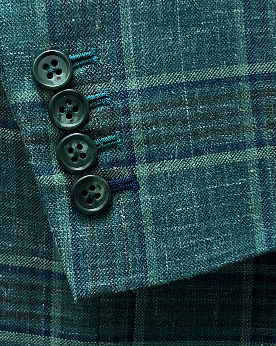 Functional sleeve buttonholes on the Westwood Hart hunter green with navy and chocolate brown plaid mens sport coat, with navy blue contrast accents on the last buttonhole.