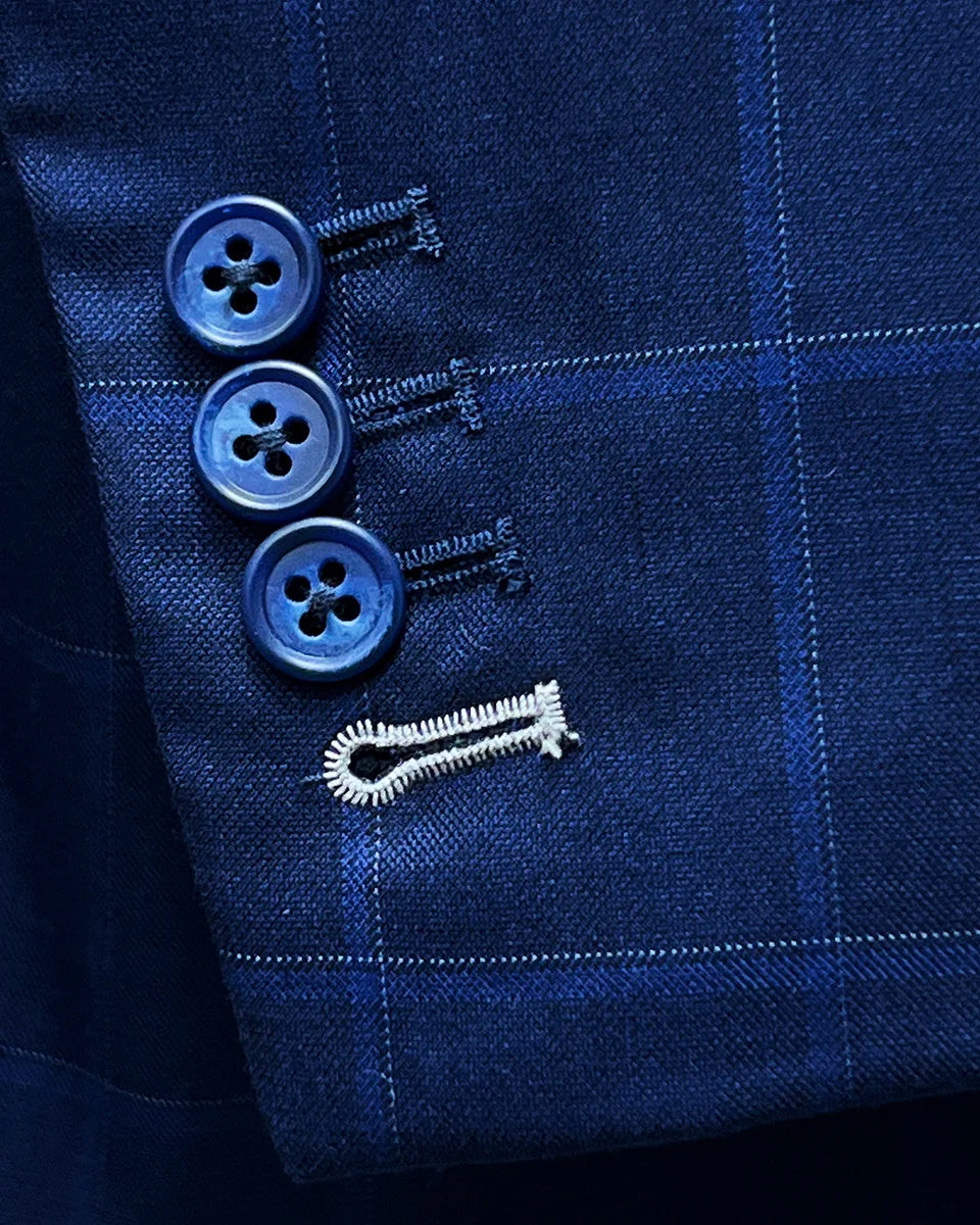 Close-up of the functional sleeve buttonholes with white contrast stitching on the royal blue suit fabric.
