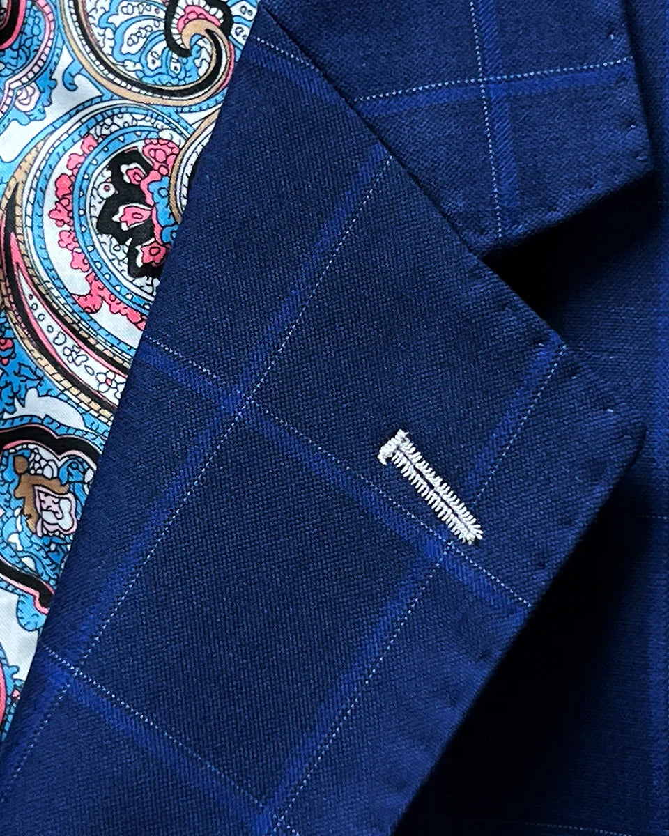 Close-up of the notch lapel with hand pick stitching on the royal blue fabric featuring a navy and white windowpane pattern.