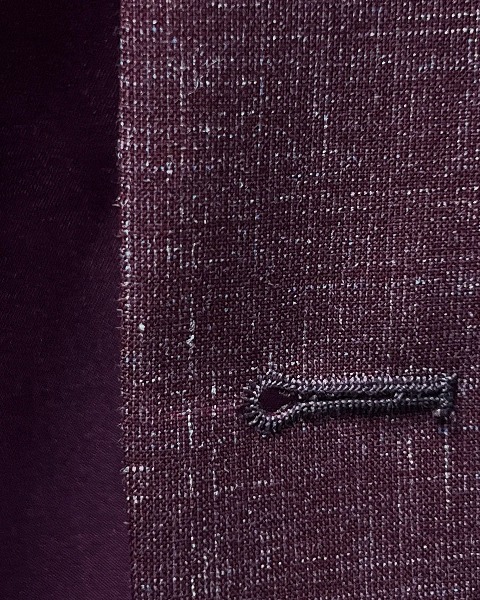 Close-up of the buttonhole stitching on a cranberry men's suit by Westwood Hart, showcasing precise tailoring.