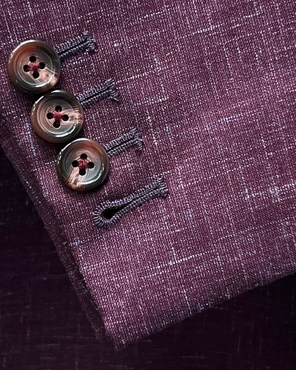 Functional sleeve buttonholes on a cranberry men's suit by Westwood Hart, emphasizing practical design and quality.