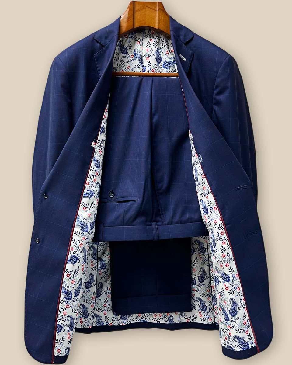 Front view of complete two-piece navy suit with subtle red windowpane pattern, showcasing the notch lapels and overall silhouette