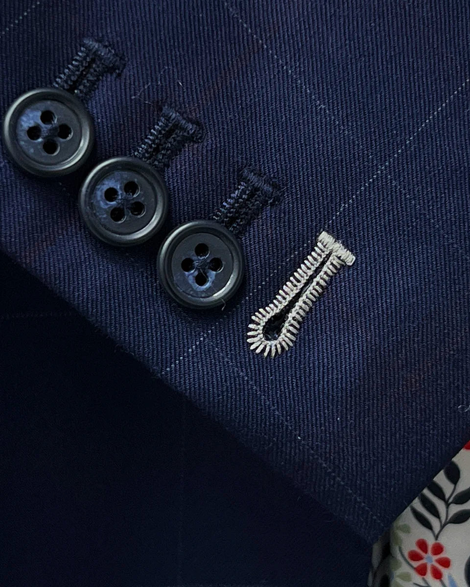 Detail shot of working sleeve buttonholes with white contrast stitching on navy suit jacket cuff