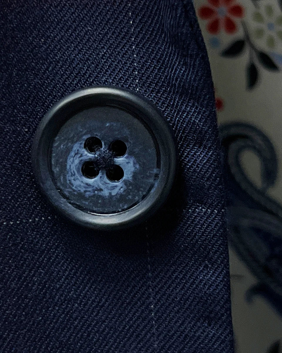 Macro shot of the navy horn buttons showing natural variations in color and texture against the suit fabric
