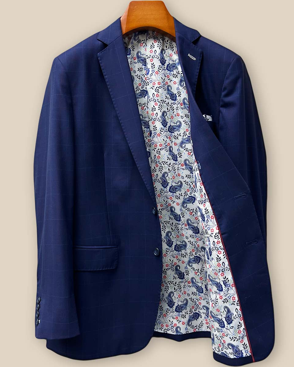 Interior left side view of the navy windowpane suit jacket, revealing white with navy and red paisley lining and inner pocket construction