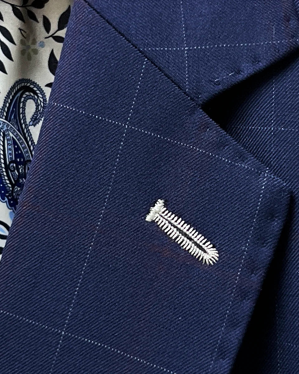 Detail of the classic notch lapel construction on the navy windowpane suit, showing the angle and proportion of the lapel