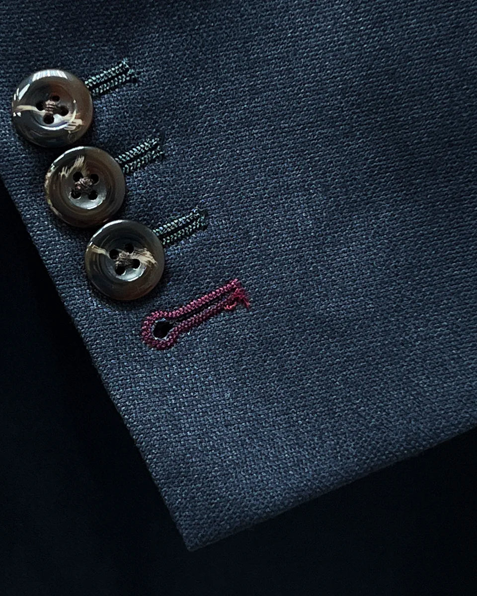Detail of contrast buttonholes on a grey suit