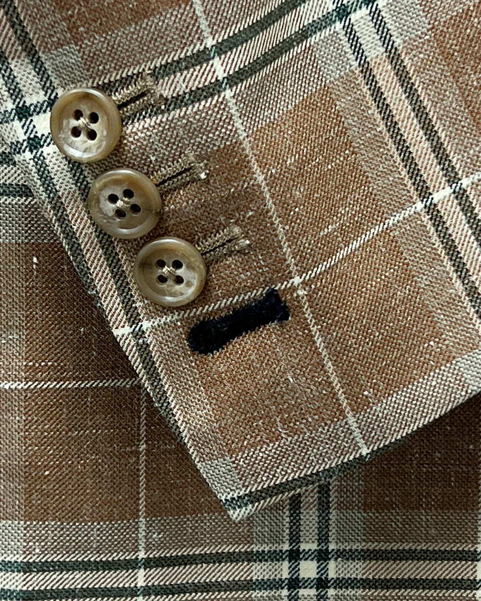 Functional sleeve buttonholes on a brown beige men's sport coat with blanched almond and midnight blue windowpane pattern.