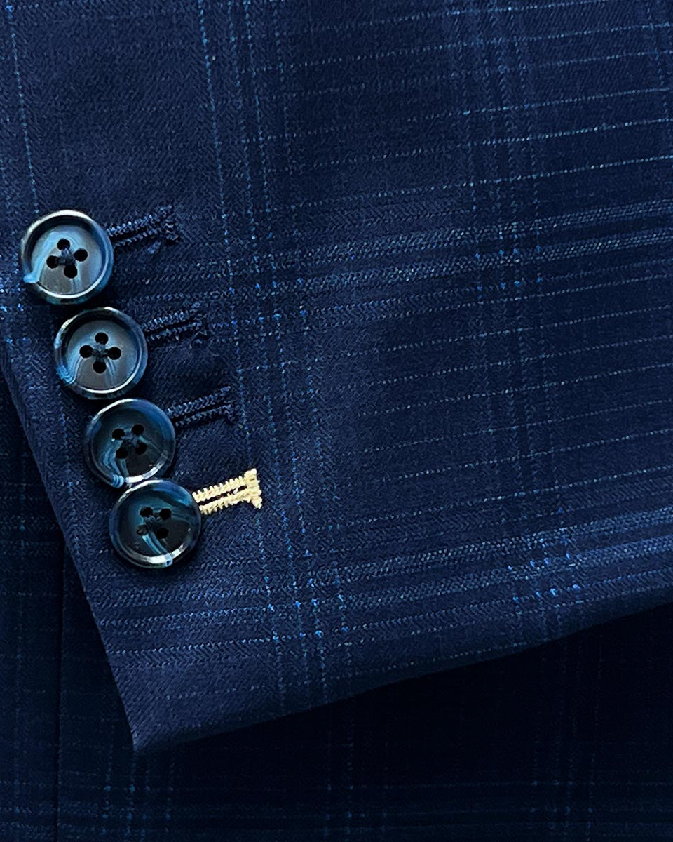Functional sleeve buttonholes allowing for precise sleeve length adjustment on a midnight blue windowpane suit.