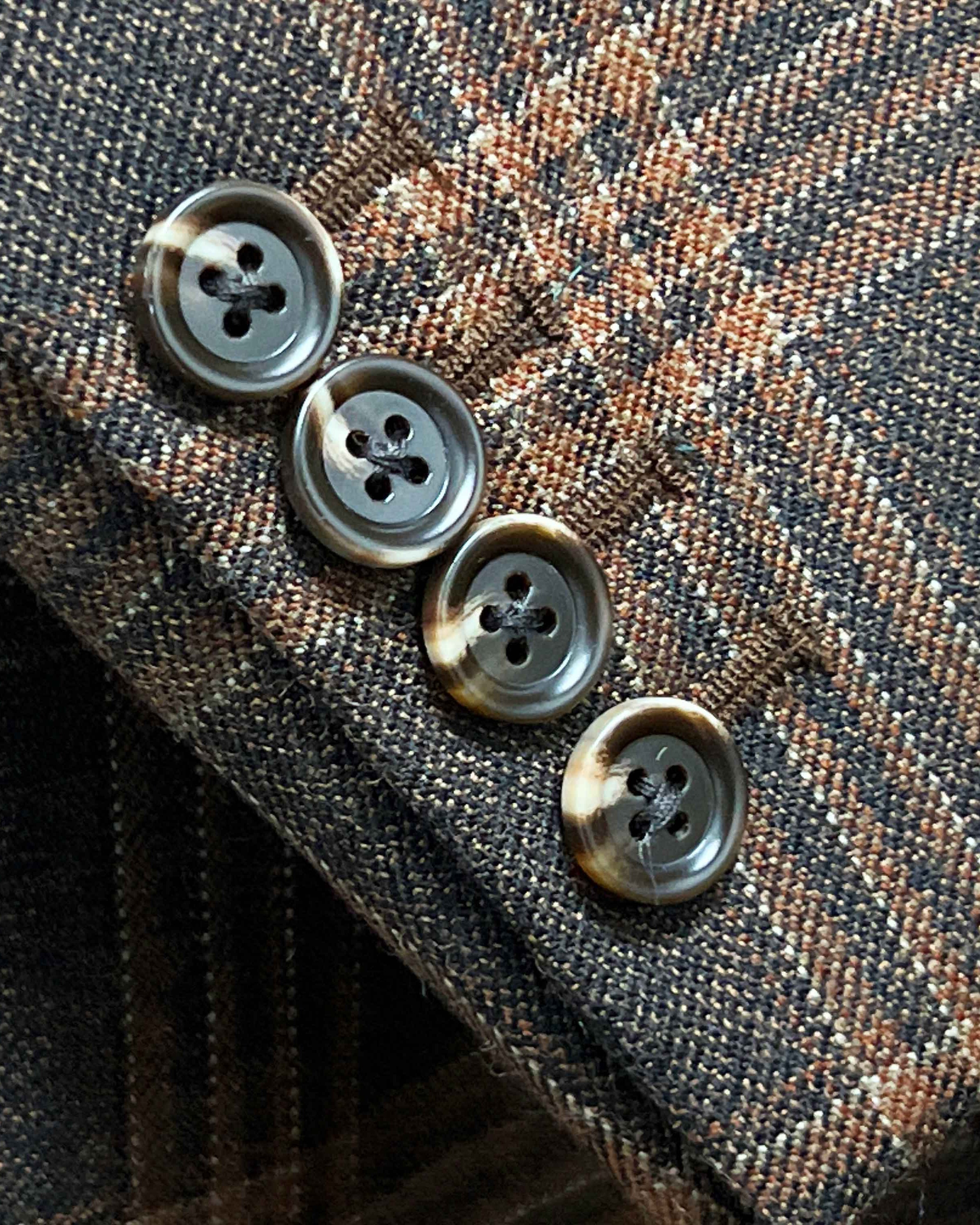 Sport coat sleeve cuff showing functional buttonholes on brown rust block windowpane tweed fabric