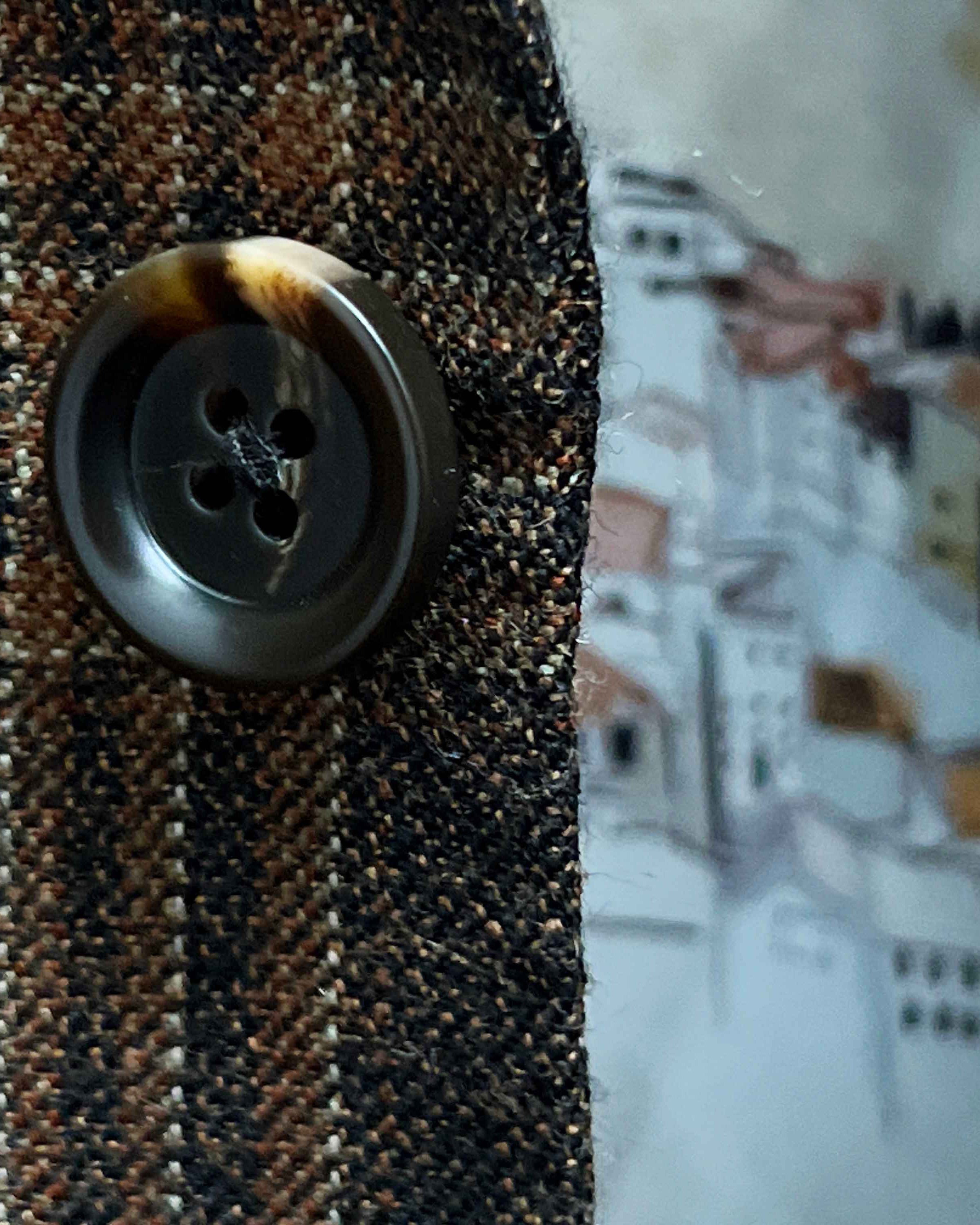 Close-up of walnut dark brown and amber horn buttons on brown rust block windowpane sport coat showing natural patterns