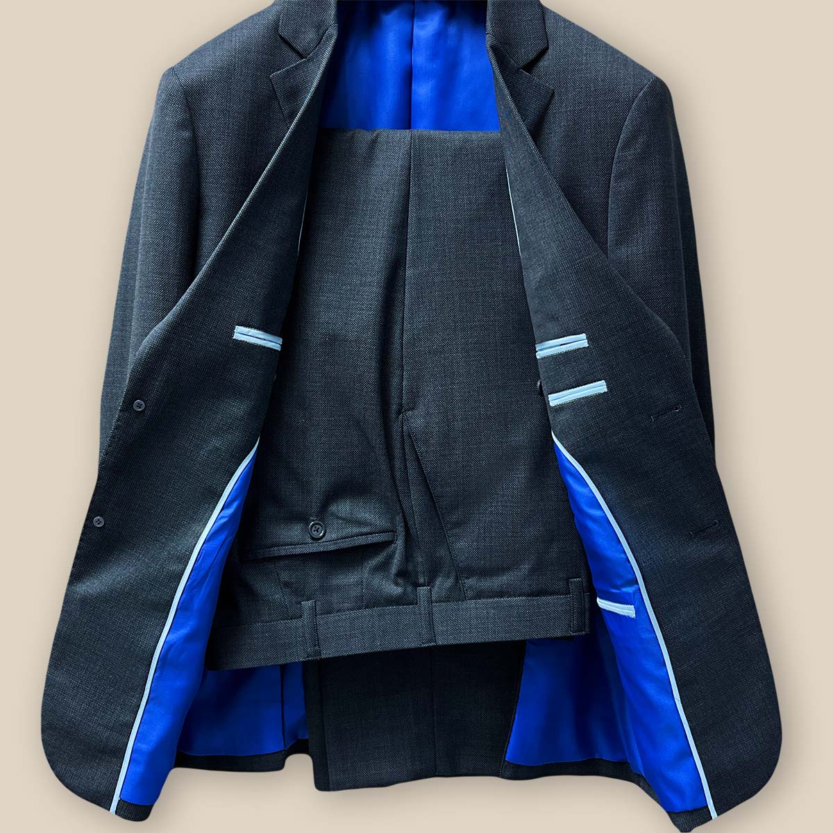 Full view of the jacket and pants revealing the complete look of a dark grey birdseye suit.