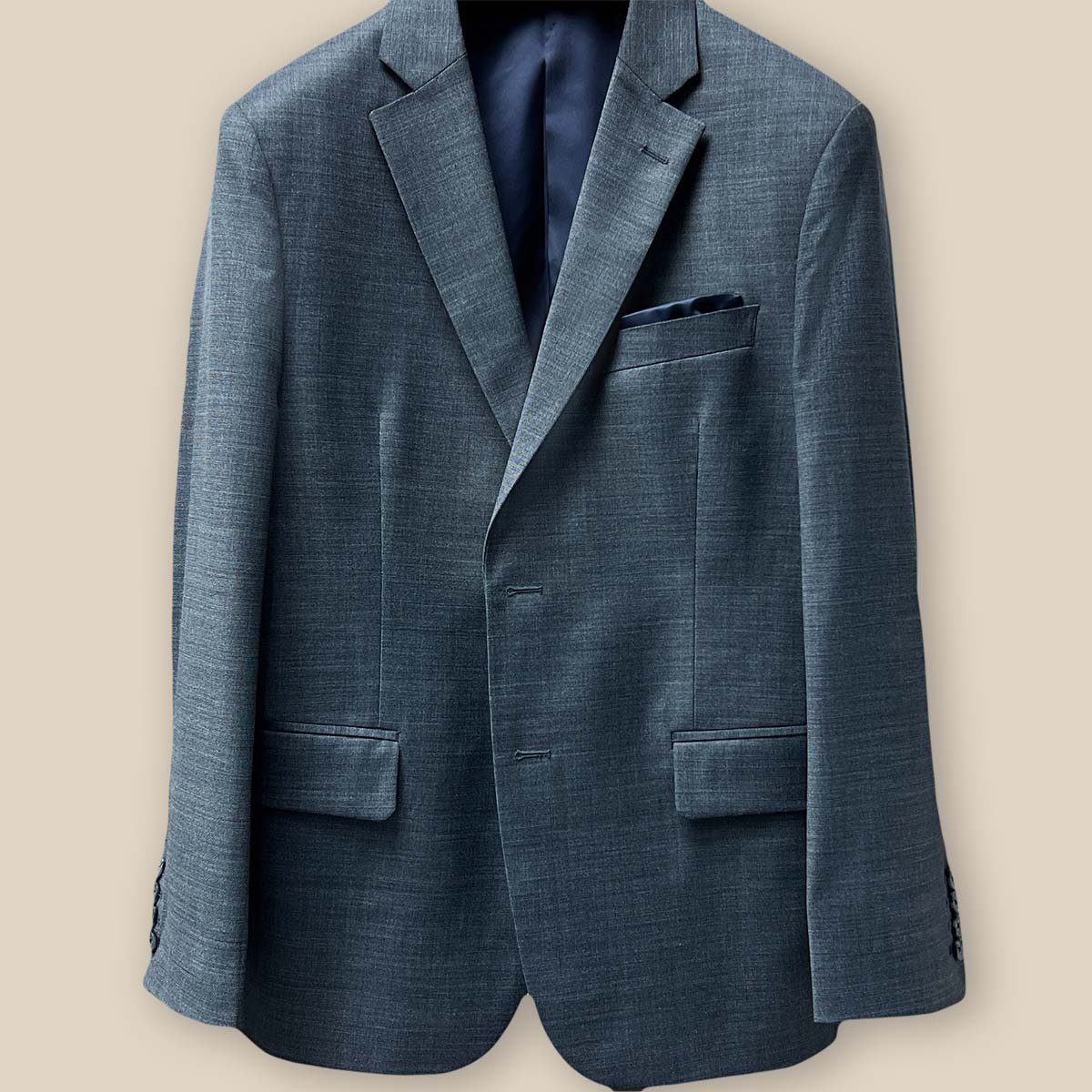Close-up of the jacket buttonhole panel, a hallmark of craftsmanship on a dark grey nailhead suit.