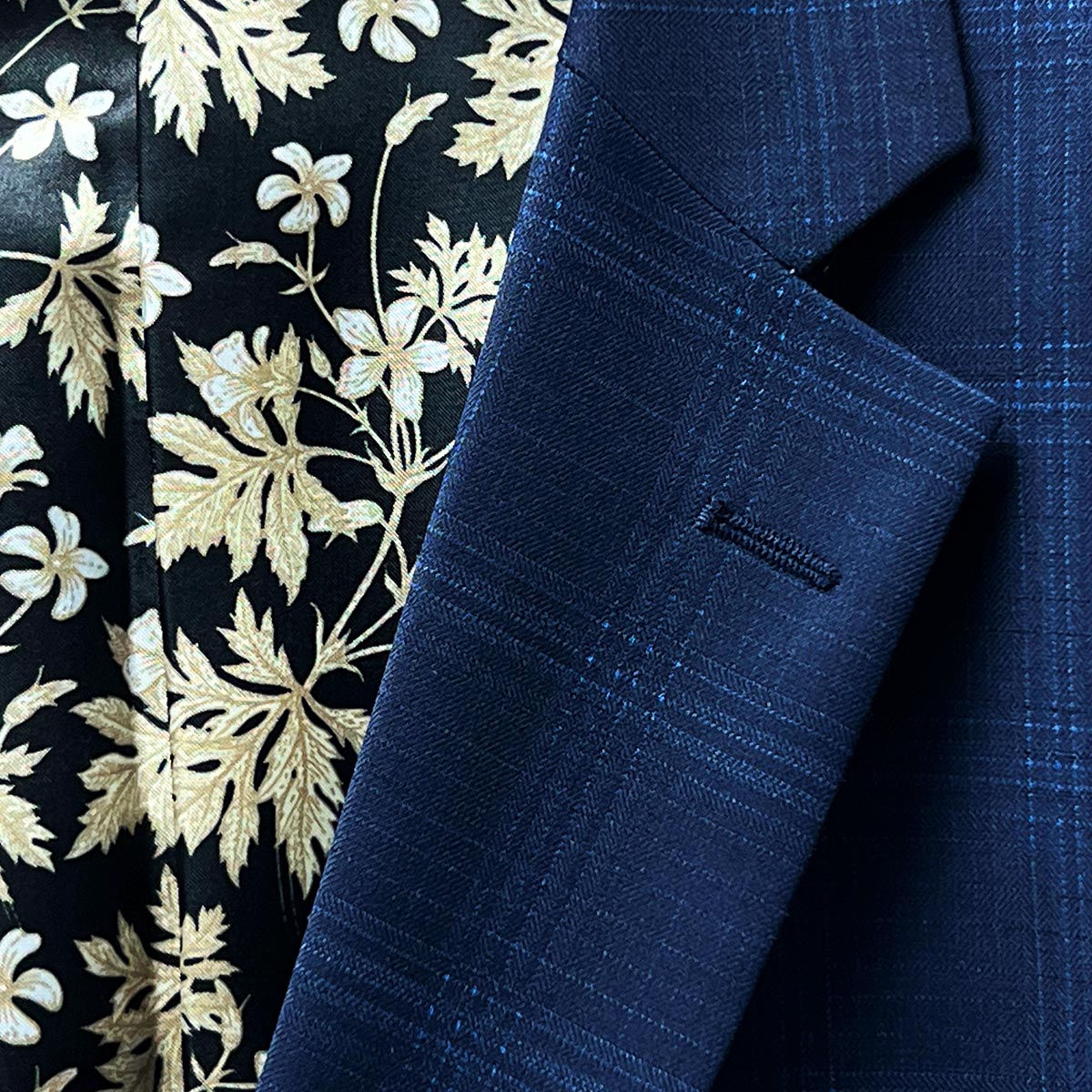 A lapel buttonhole indicating a readiness for a boutonnière on a midnight blue windowpane suit.
