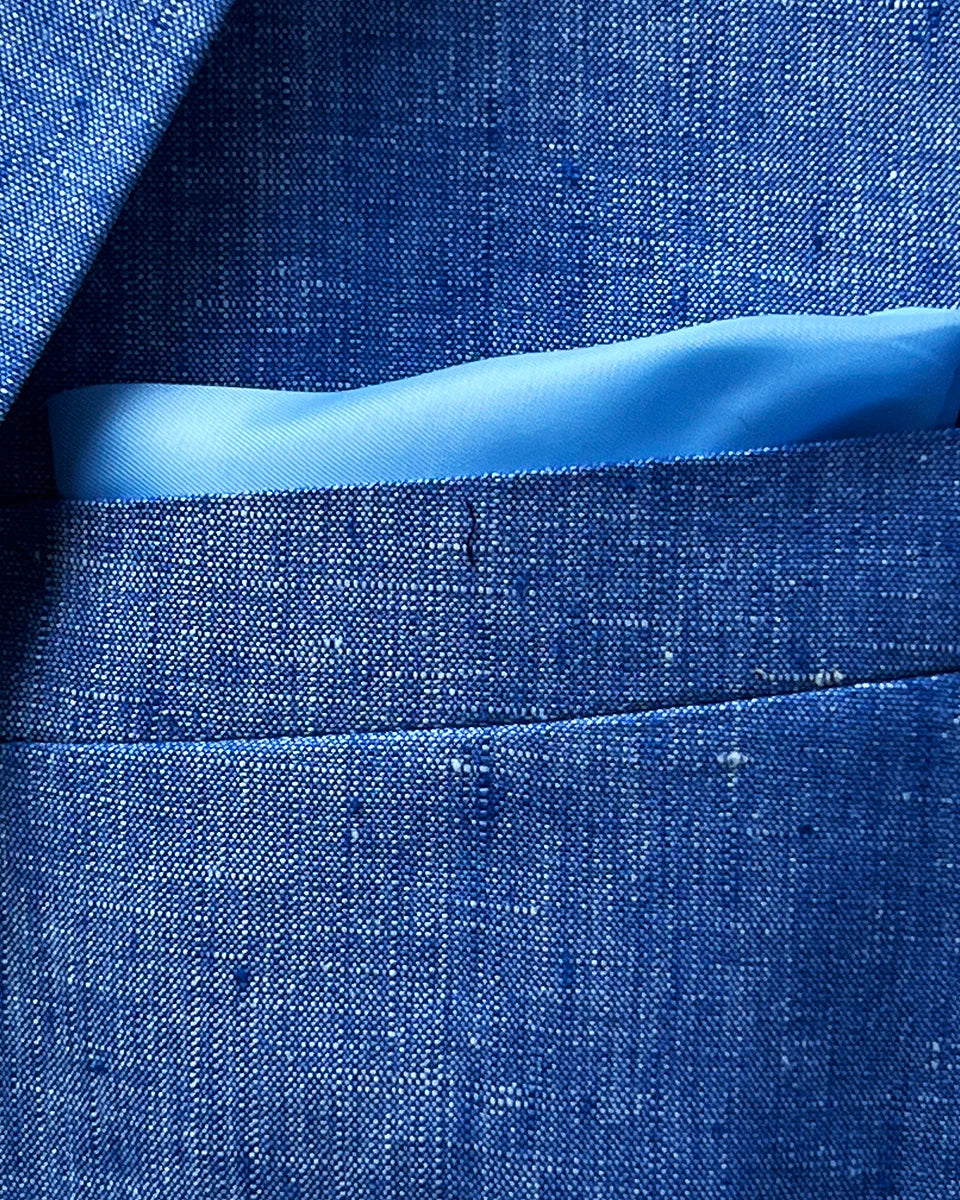 Close-up of light blue solid Irish linen men's suit jacket breast pocket with built-in pocket square detail