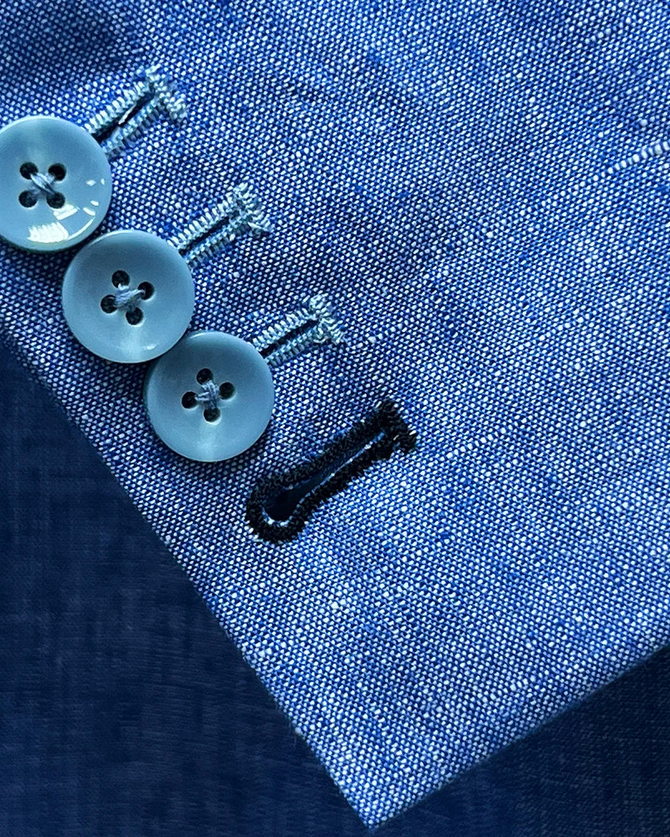 Detail of light blue solid Irish linen men's suit jacket sleeve showing functional buttonholes, including royal blue accent buttonhole