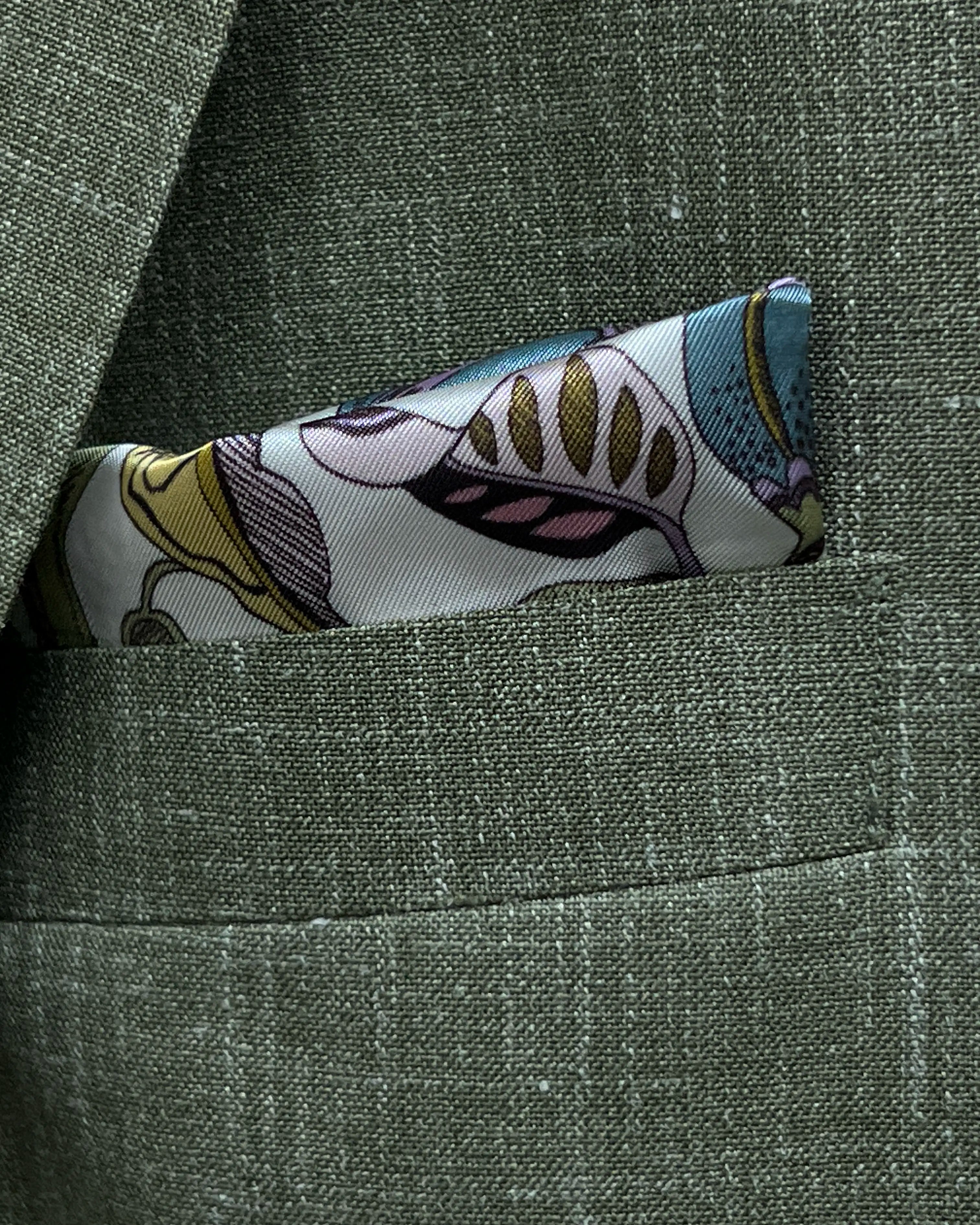 Breast pocket of sage green plain men's suit showing matching botanical print lining pocket square