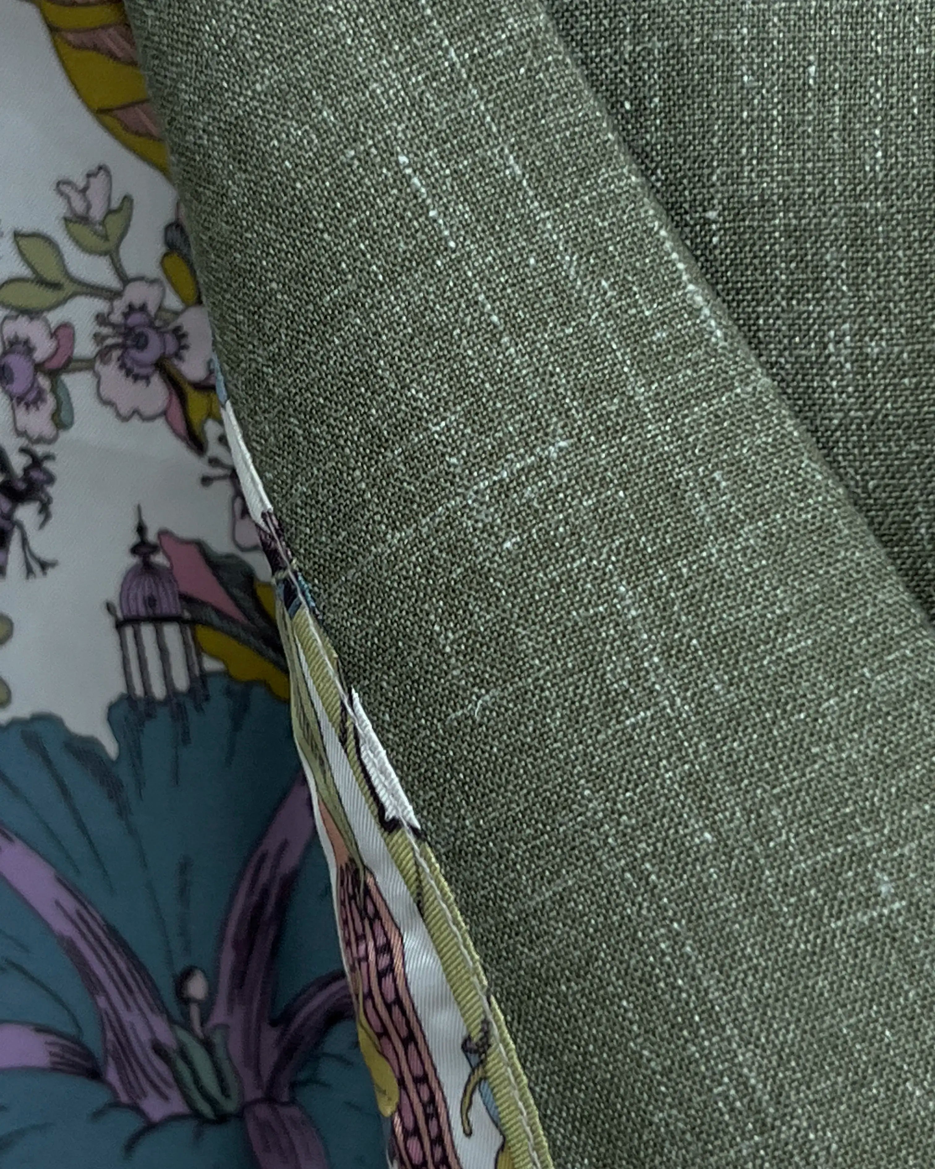 Close-up of Loro Piana fabric on sage green plain men's suit showing open weave slub texture