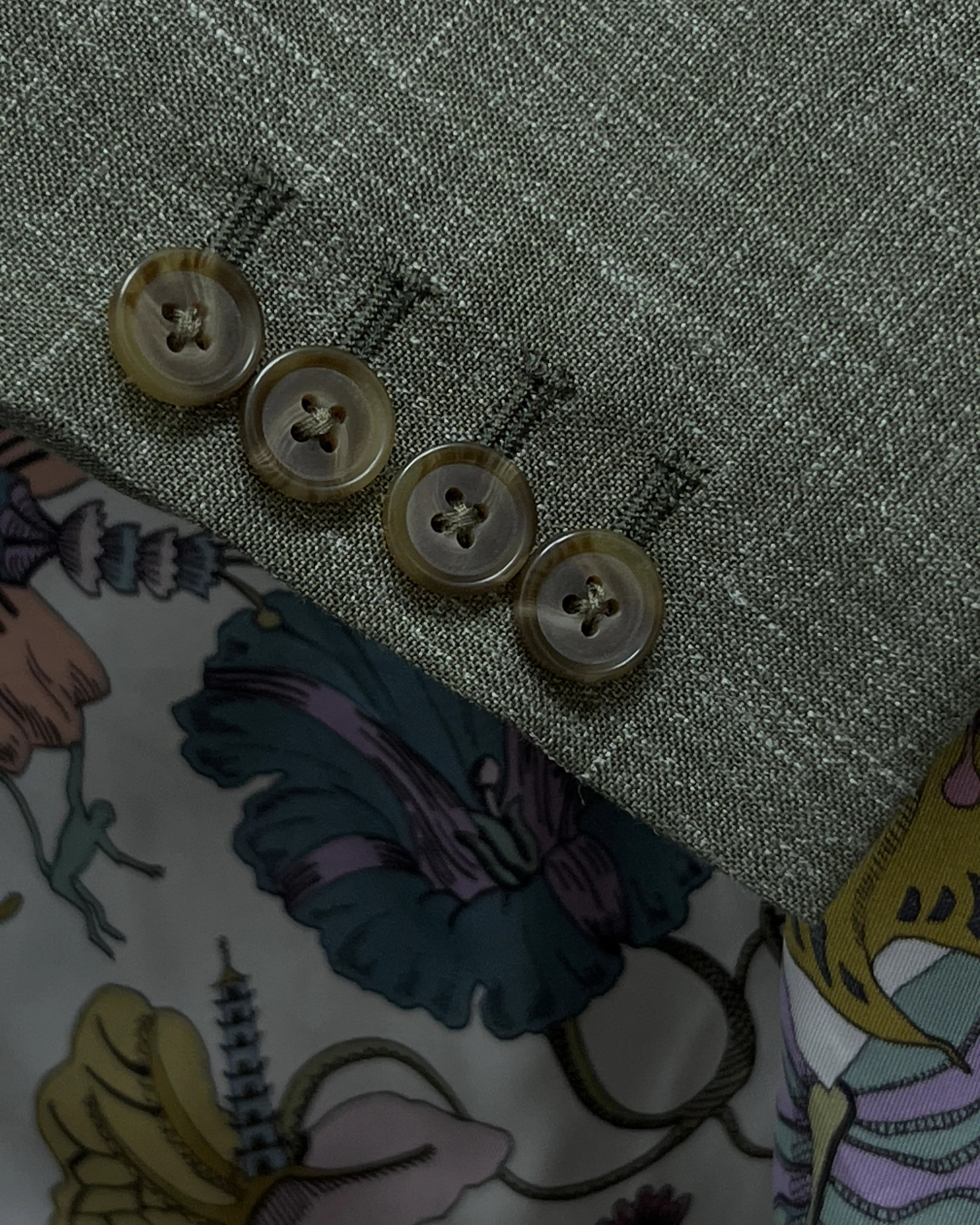 Sleeve cuff of sage green plain men's suit showing four functional surgeon's buttonholes