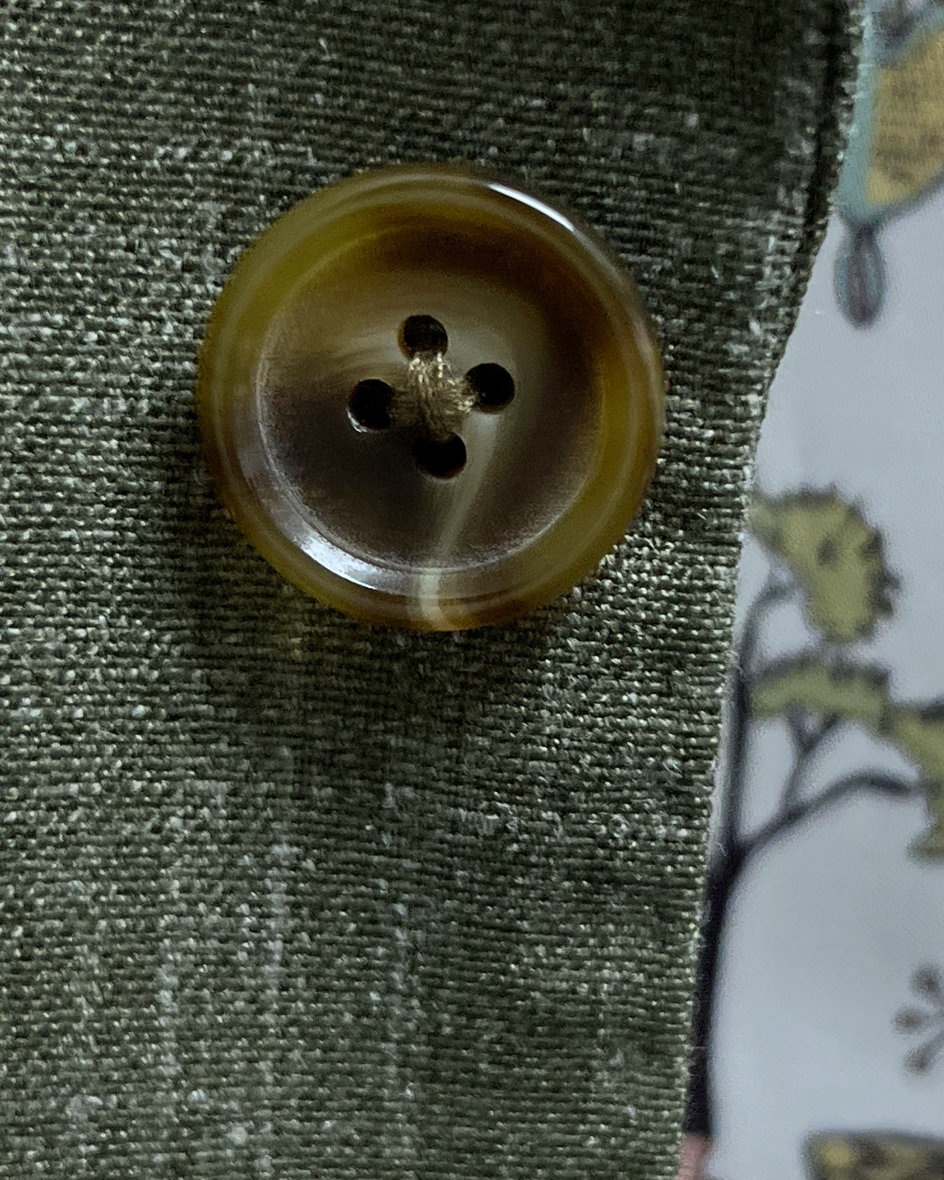 Close-up of olive khaki horn buttons on sage green plain men's suit