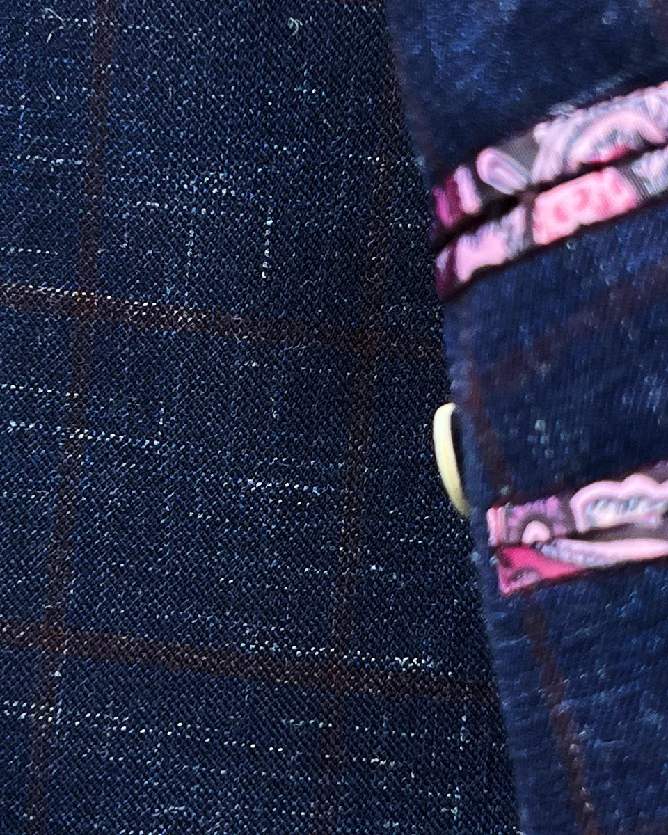 Close-up of lapel buttonhole with ruby red contrast stitching on navy windowpane sport coat peak lapel showing precision tailoring work