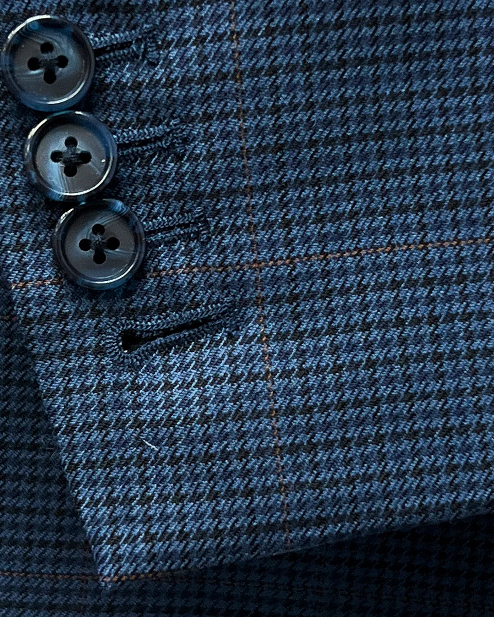 Functional sleeve buttonholes of the prussian blue suit jacket, showcasing navy marble horn buttons and precise stitching.