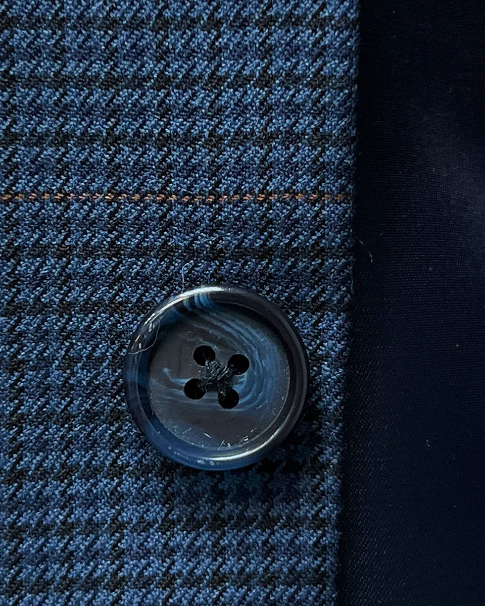 Close-up of the navy marble horn buttons on the prussian blue suit jacket, highlighting their unique texture and color.