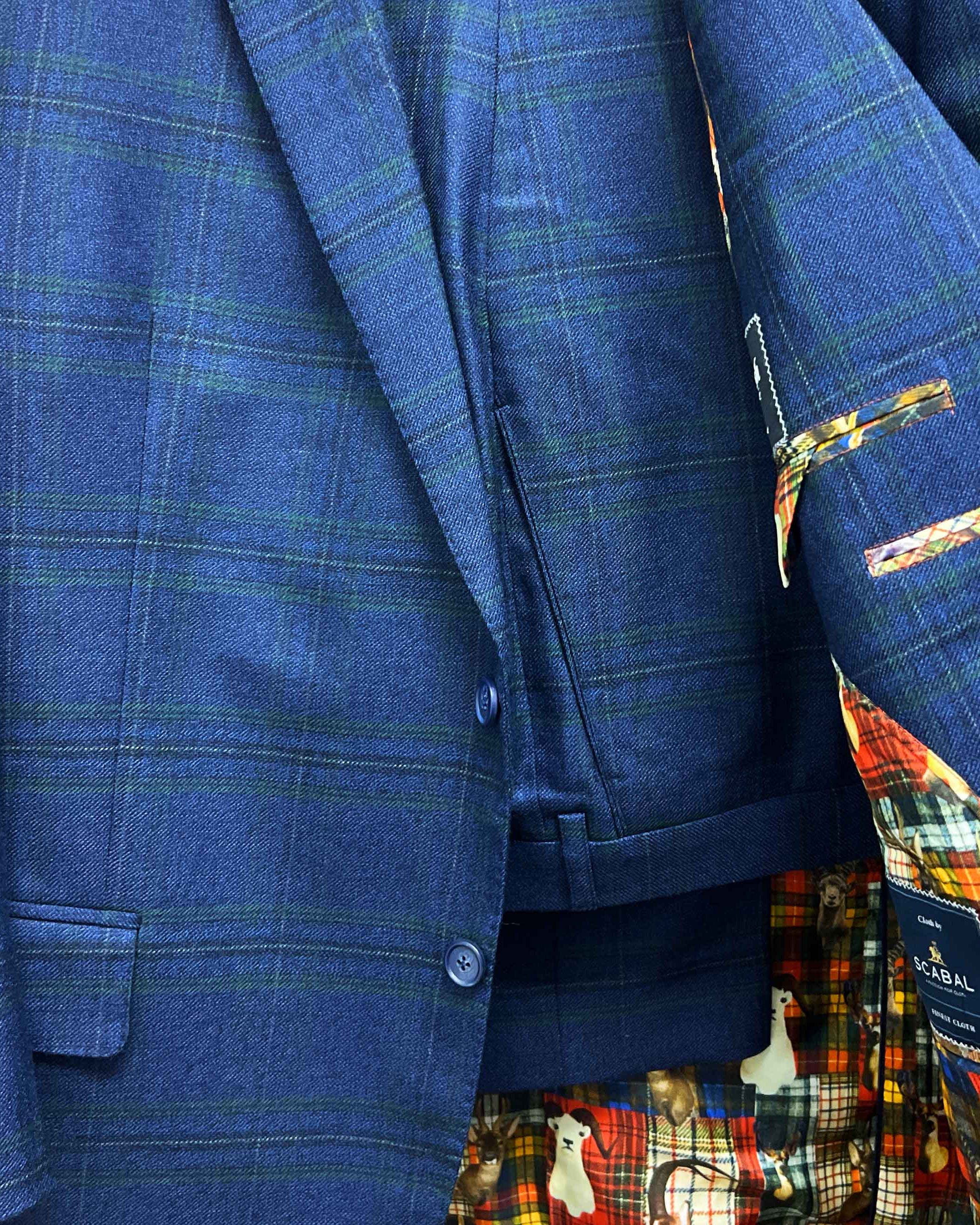 Complete two-piece deep blue navy emerald green overcheck custom suit displayed on hanger showing jacket and trousers with plaid pattern