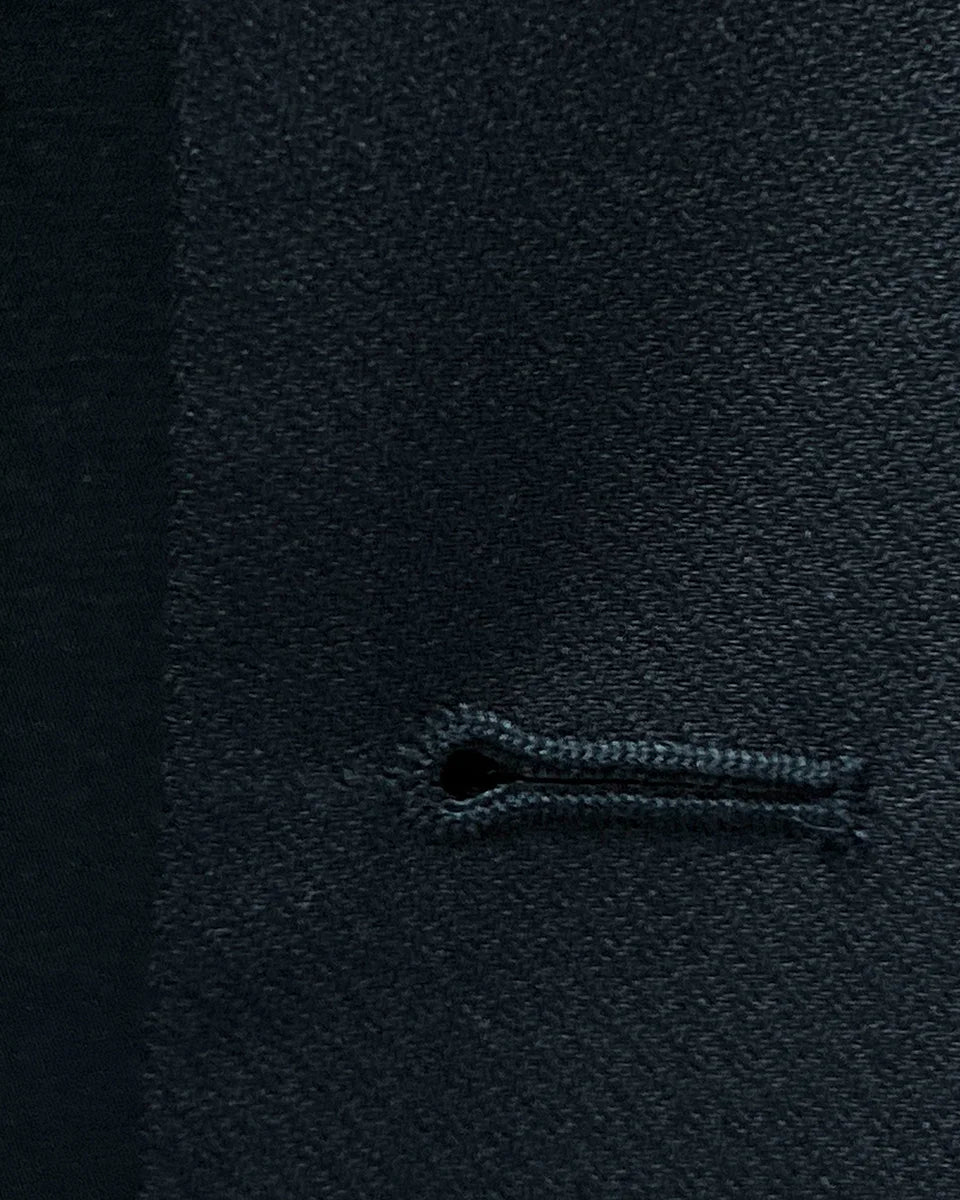 Macro view of precise buttonhole stitching on a black self-textured jacquard suit