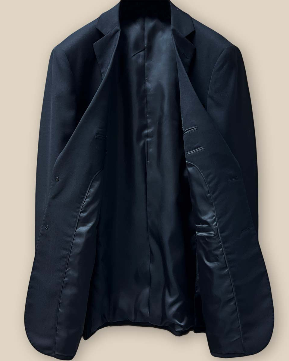 Full interior view of a black self-textured jacquard suit jacket, highlighting the smooth black Bemberg silk lining