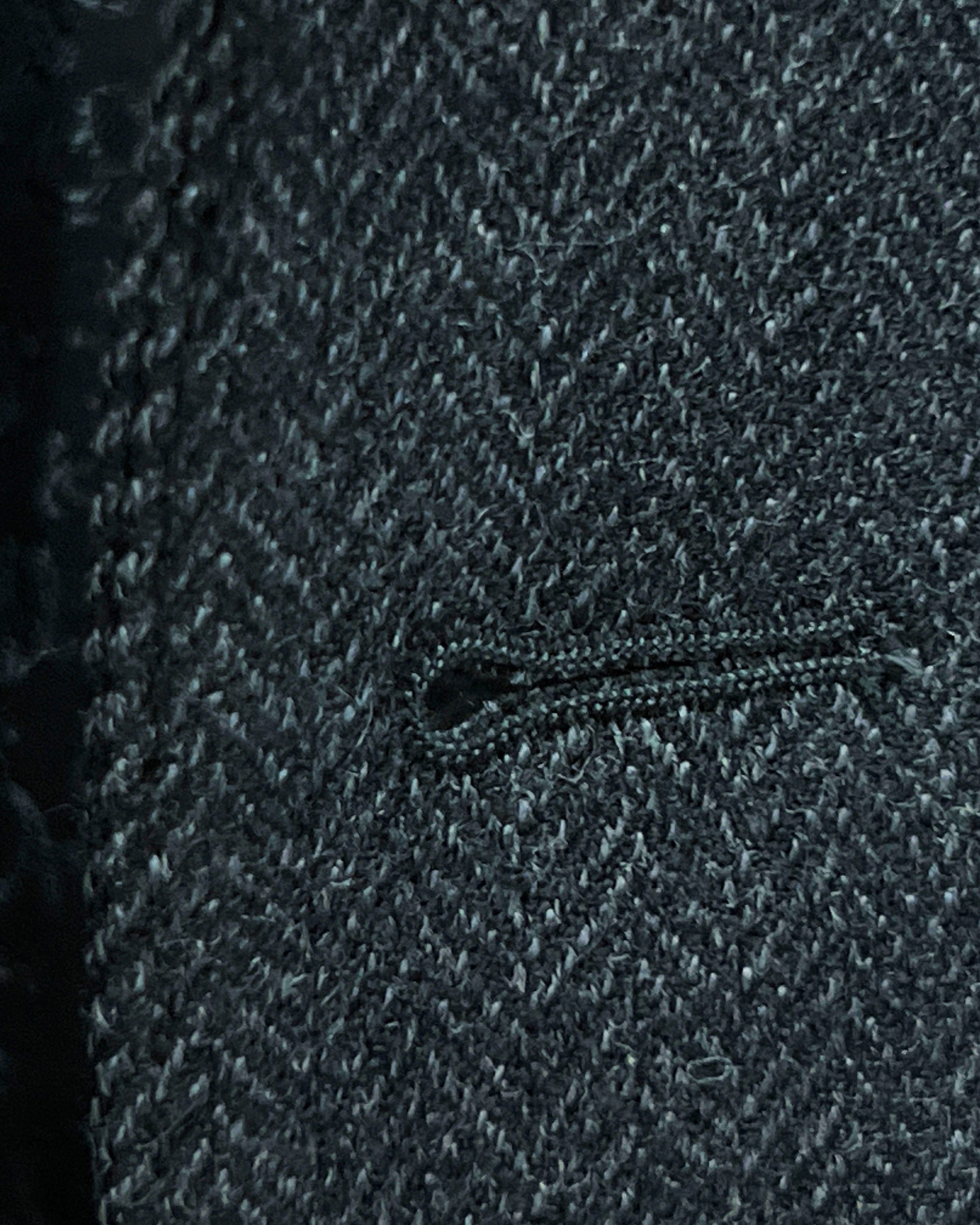 Detailed macro shot of hand-finished buttonhole stitching on charcoal grey herringbone sport coat with edge pick stitching