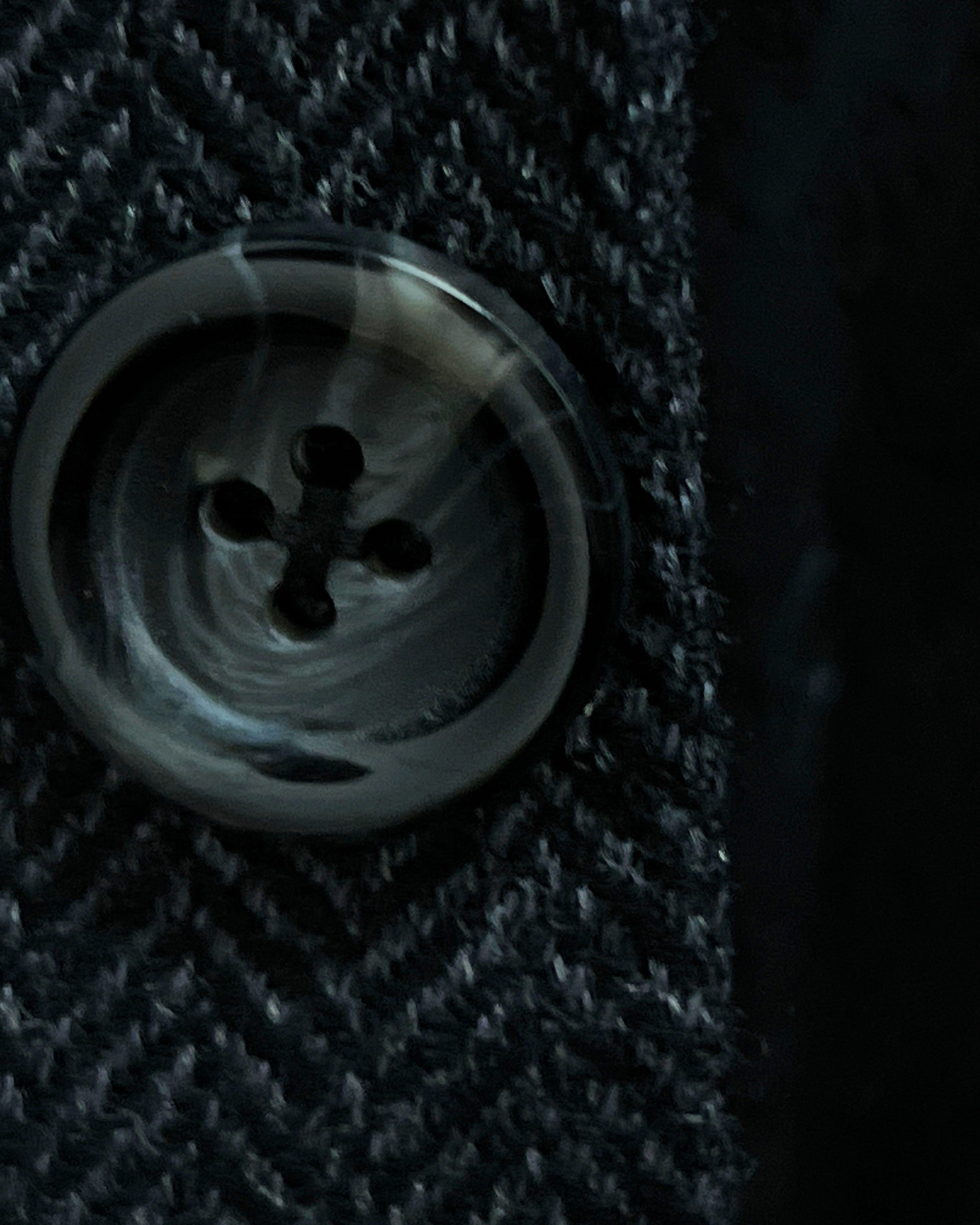 Close-up of charcoal horn buttons with light grey marbling on charcoal grey herringbone sport coat showing natural patterns