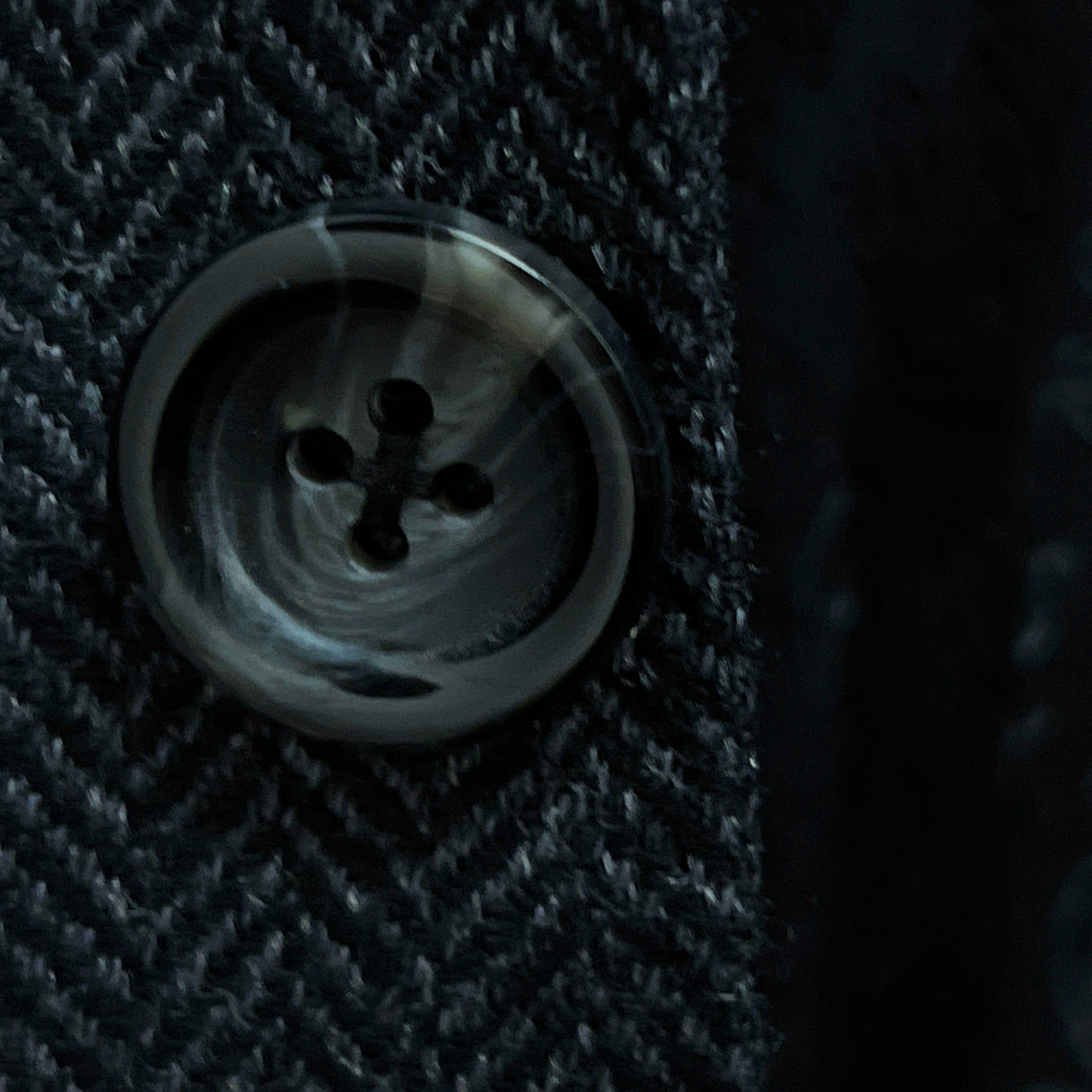 Close-up of charcoal horn buttons with light grey marbling on charcoal grey herringbone sport coat showing natural patterns