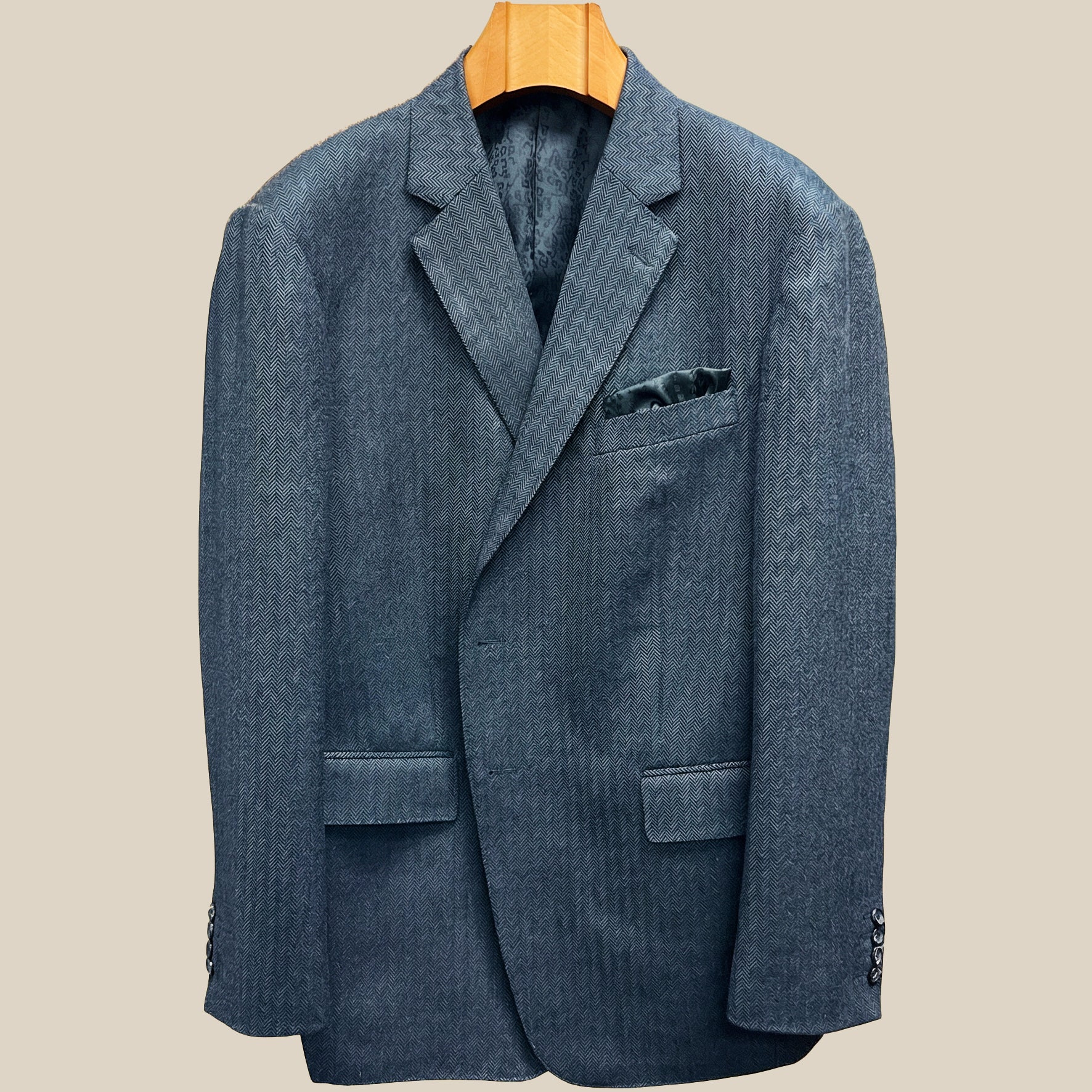 Close-up view of charcoal grey herringbone sport coat showing contrast edge pick stitching detail on buttonhole panel