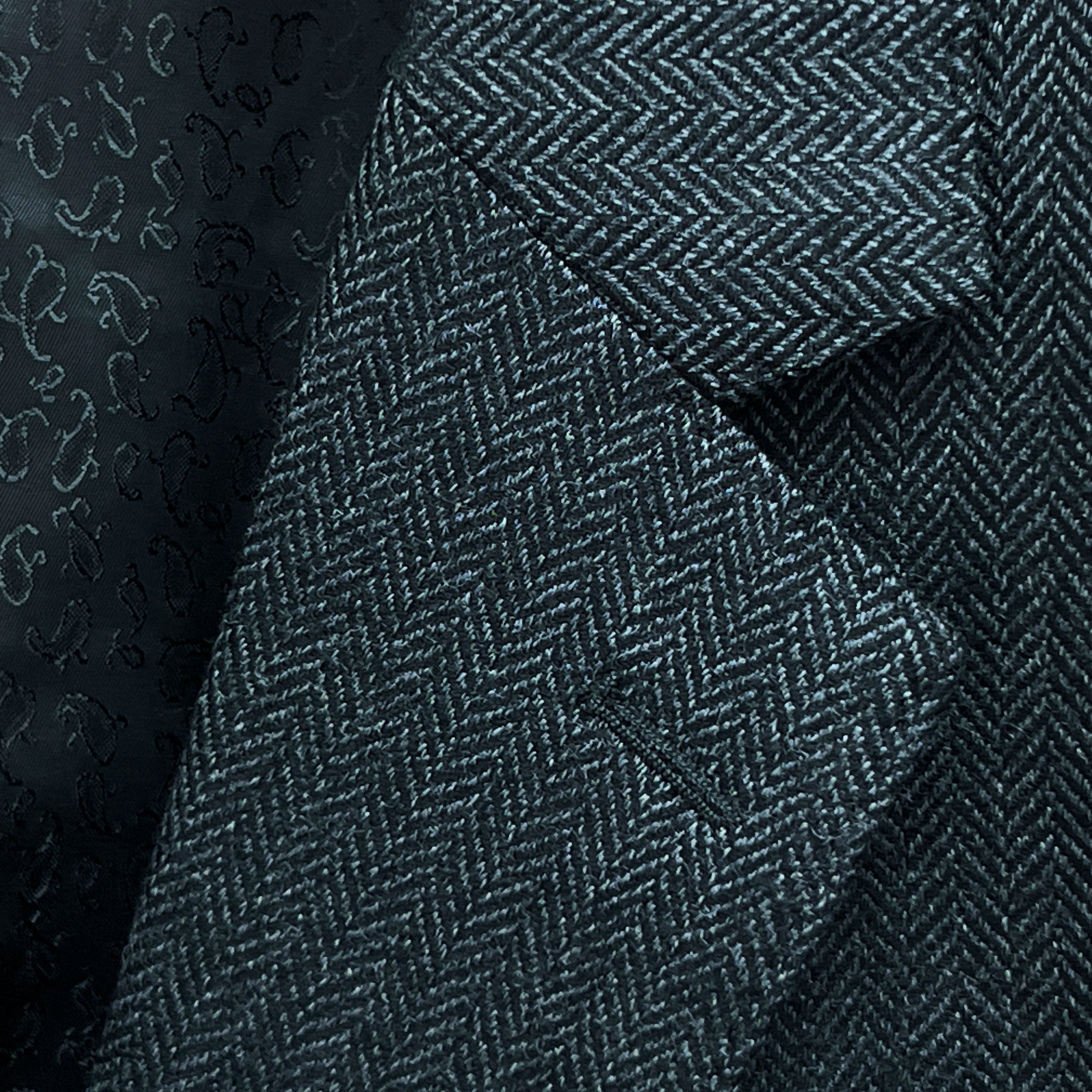 Classic notch lapel detail on charcoal grey herringbone sport coat showing hand pick stitching and herringbone weave pattern