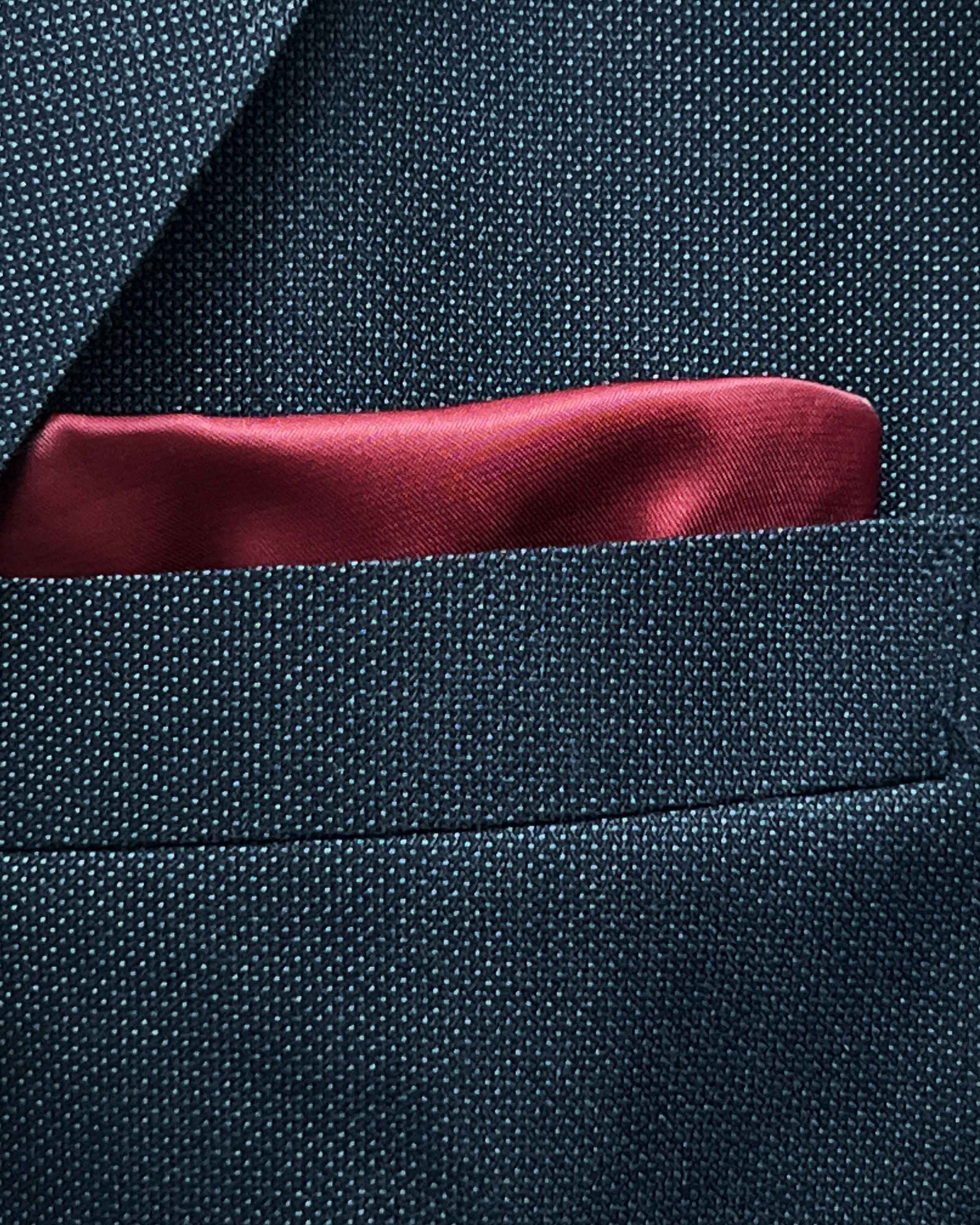 Breast pocket of dark charcoal grey birdseye suit jacket with built-in pocket square holder and hand-finished edges