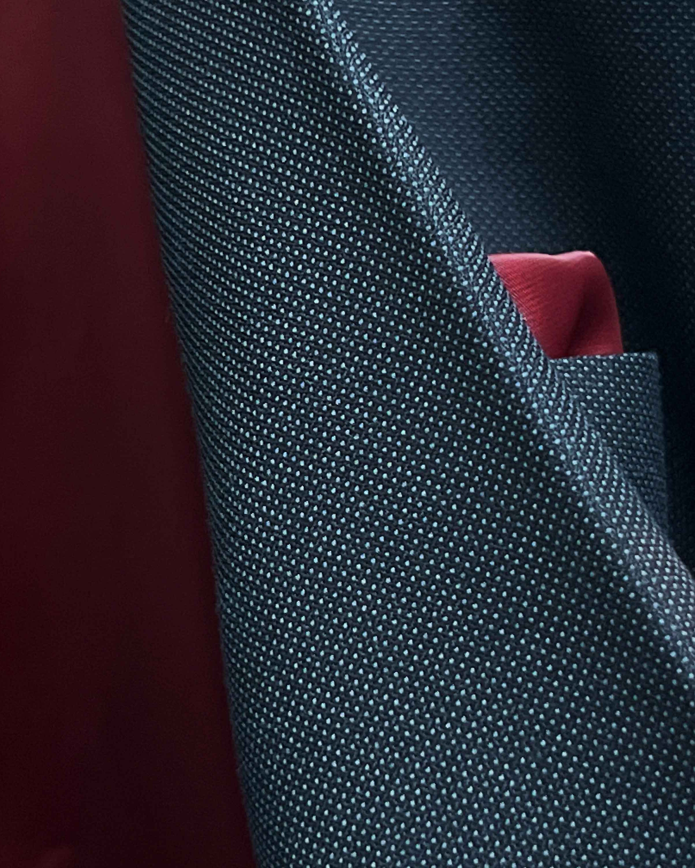 Macro detail shot of birdseye weave texture on dark charcoal grey Super 130s merino wool fabric showing intricate pattern