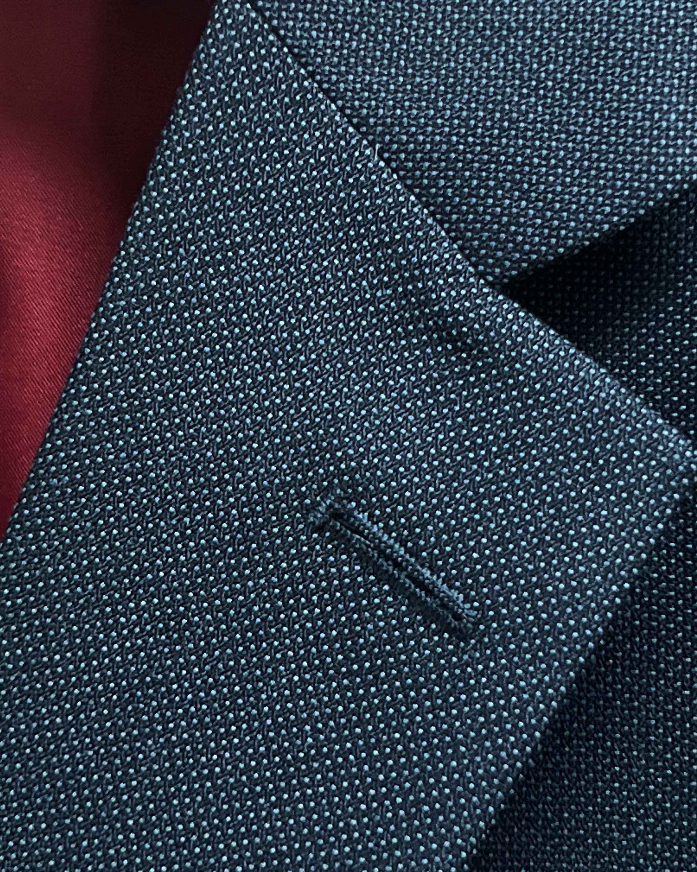 Classic notch lapel detail on dark charcoal grey birdseye suit jacket showing hand pick stitching and textured weave pattern