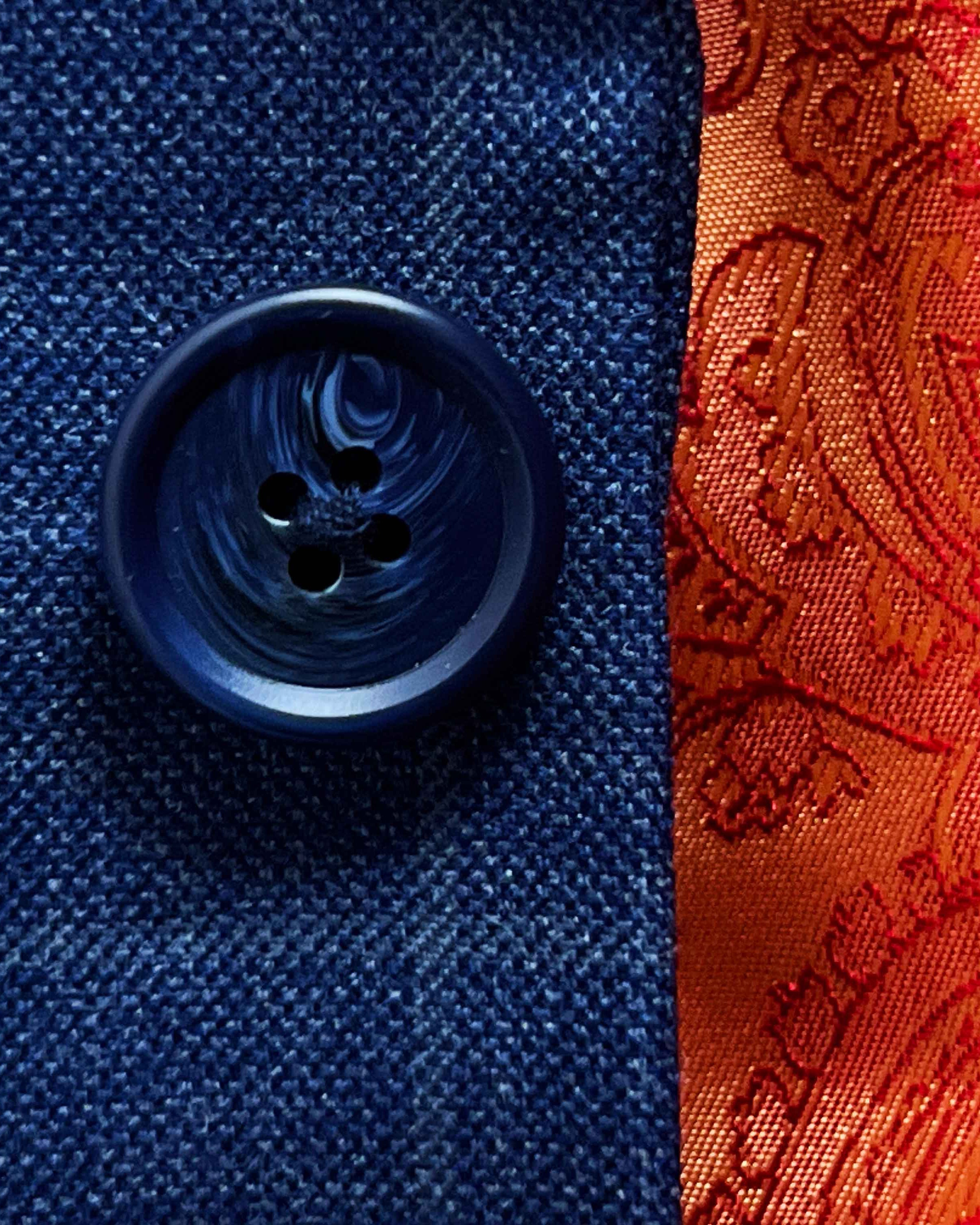 Close-up of marbled dark blue horn buttons on deep blue windowpane check suit jacket showing natural marble-like patterns
