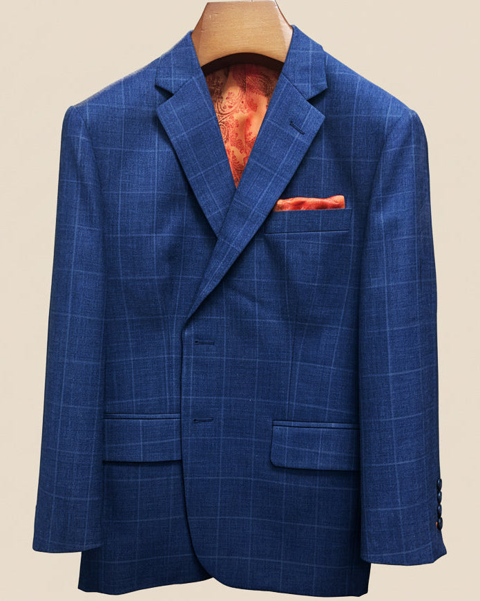 Close-up view of deep blue windowpane check suit jacket showing contrast orange accent buttonhole with hand-finished stitching detail