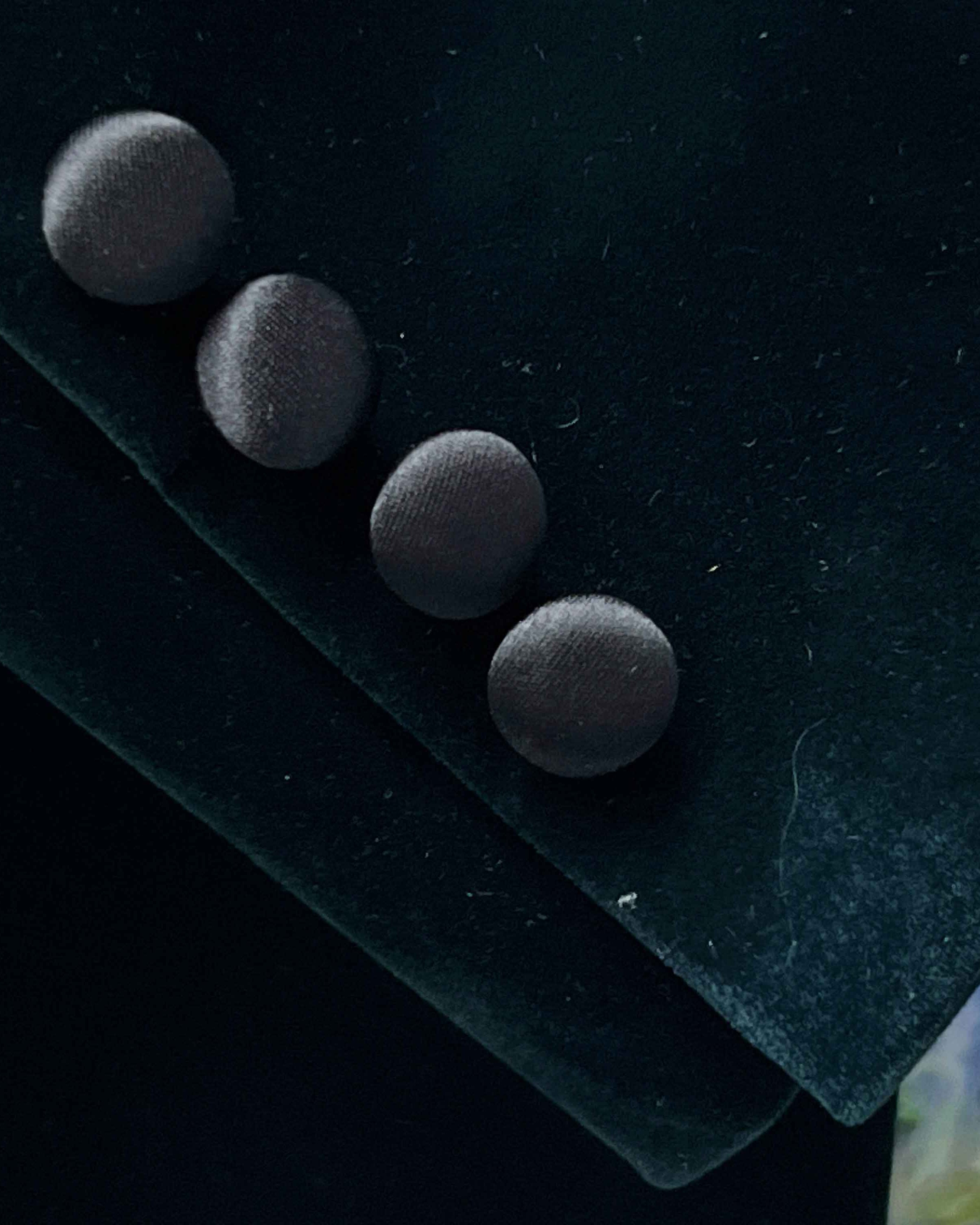 Four black buttons on a dark fabric surface