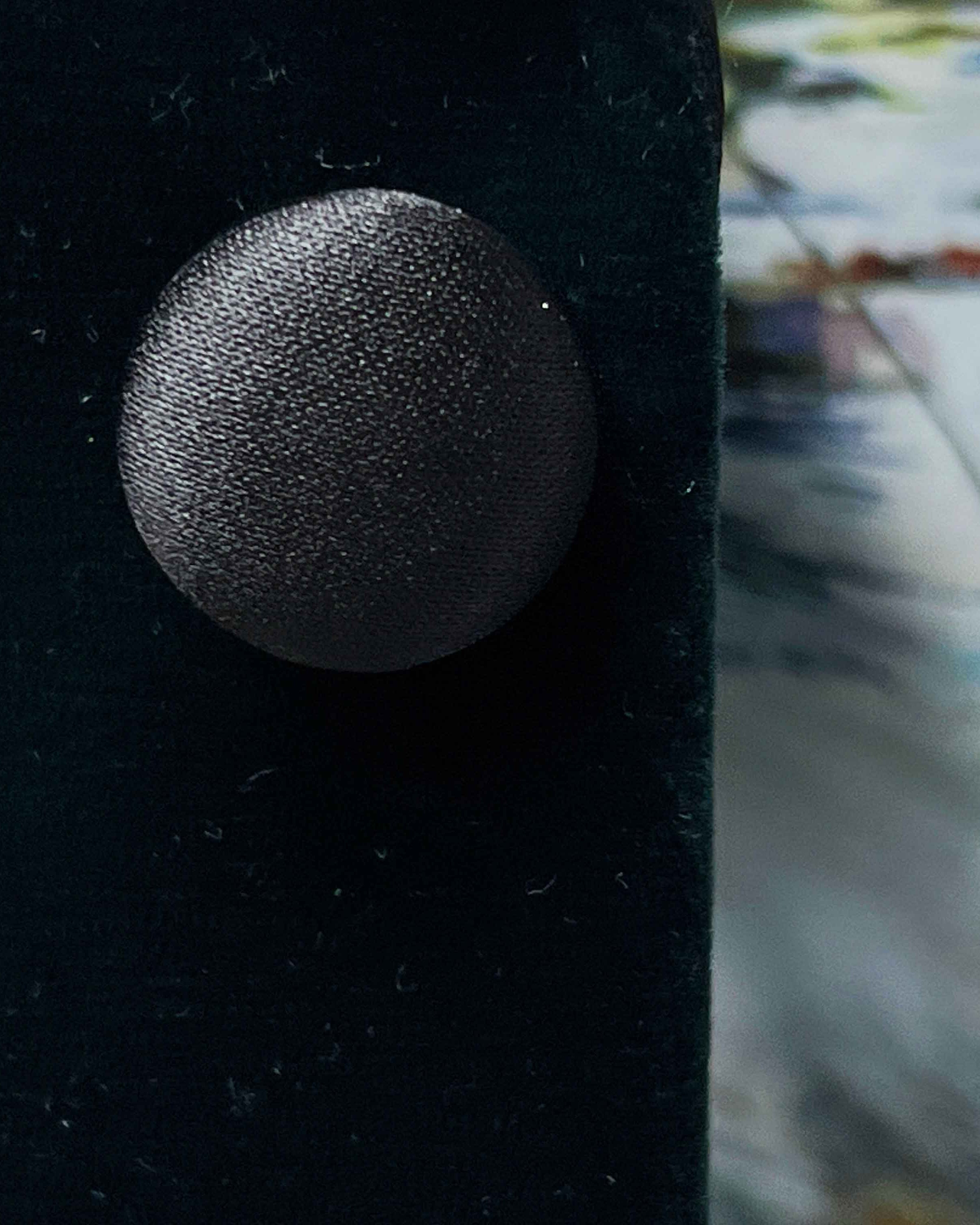 Close-up of a textured black button on a dark fabric background