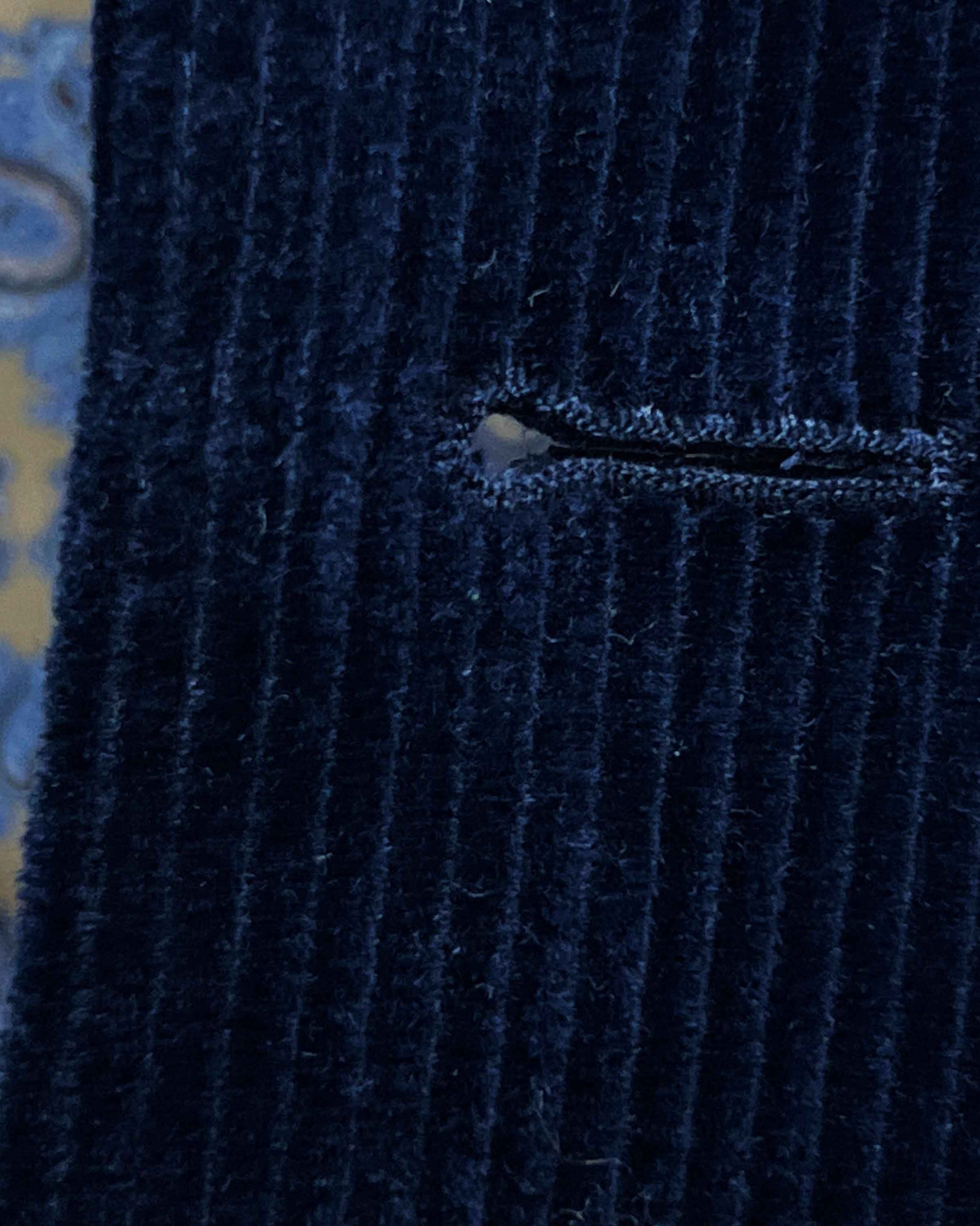 Detailed macro shot of hand-finished buttonhole stitching on deep navy blue corduroy sport coat with light blue contrast thread