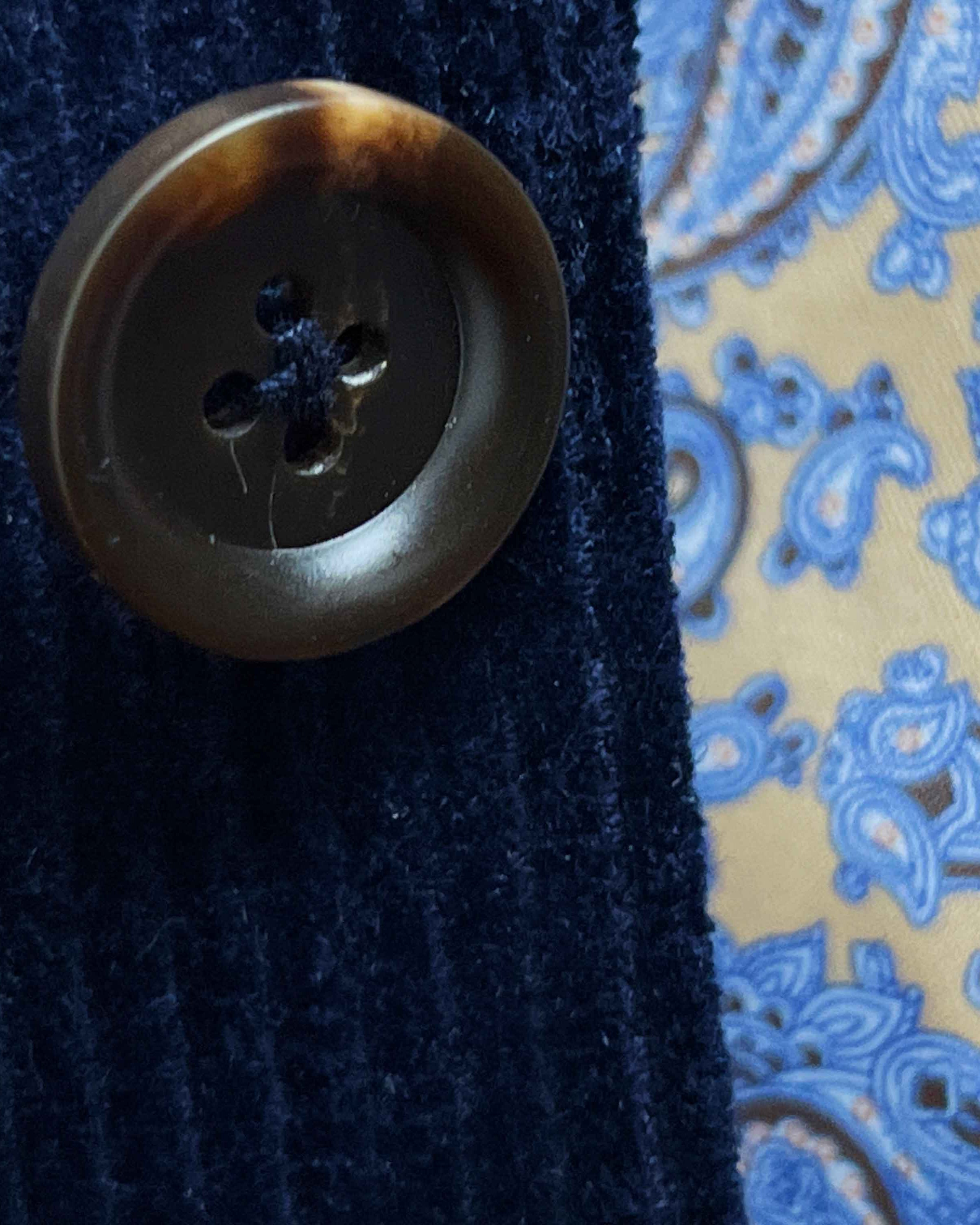 Close-up of tortoiseshell brown horn buttons on deep navy blue corduroy sport coat showing natural patterns